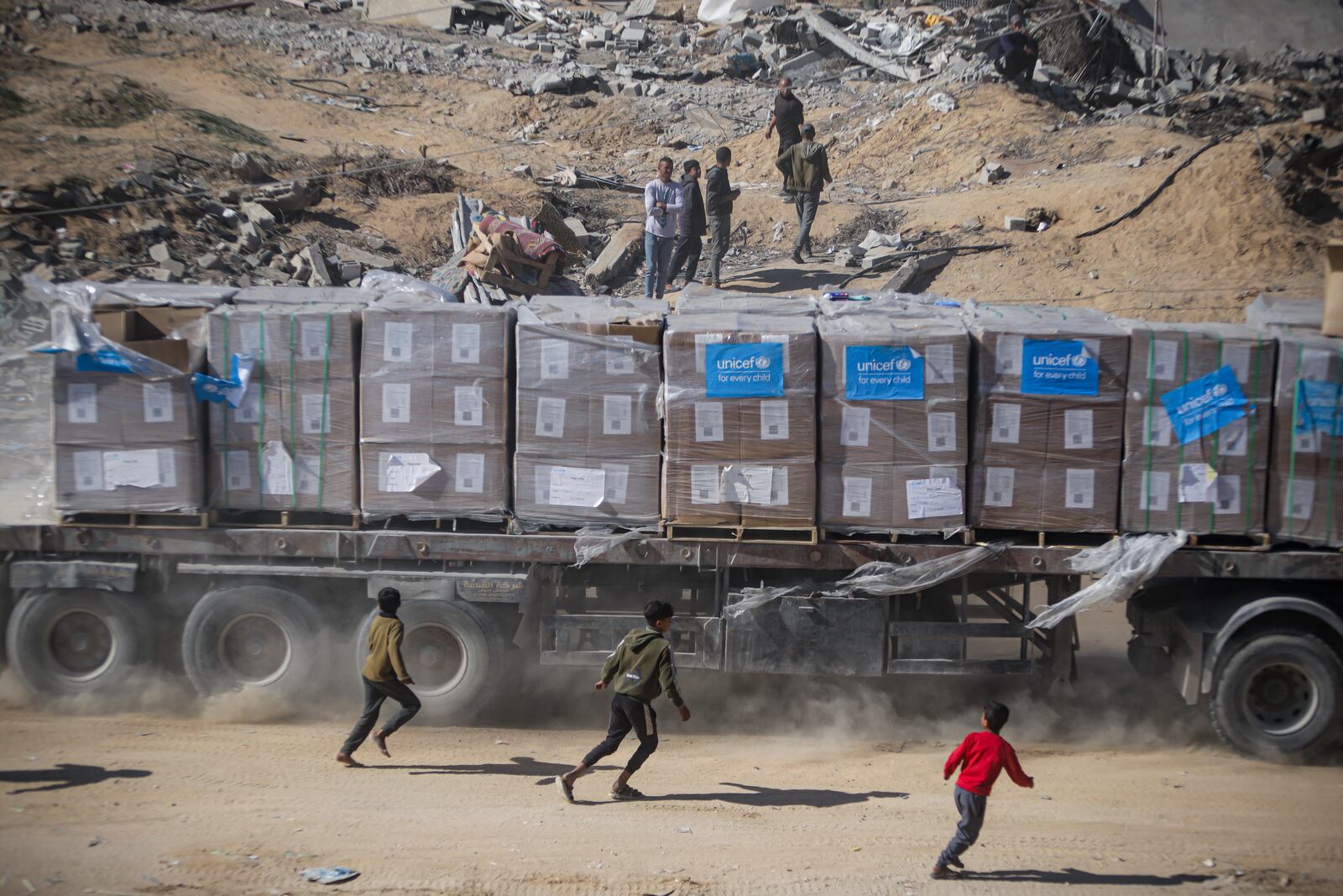 Palestinians chase humanitarian aid trucks that arrived through the Kerem Shalom crossing from Egypt into the Gaza Strip, in Rafah, Tuesday, Jan. 21, 2025. (AP Photo/Jehad Alshrafi)