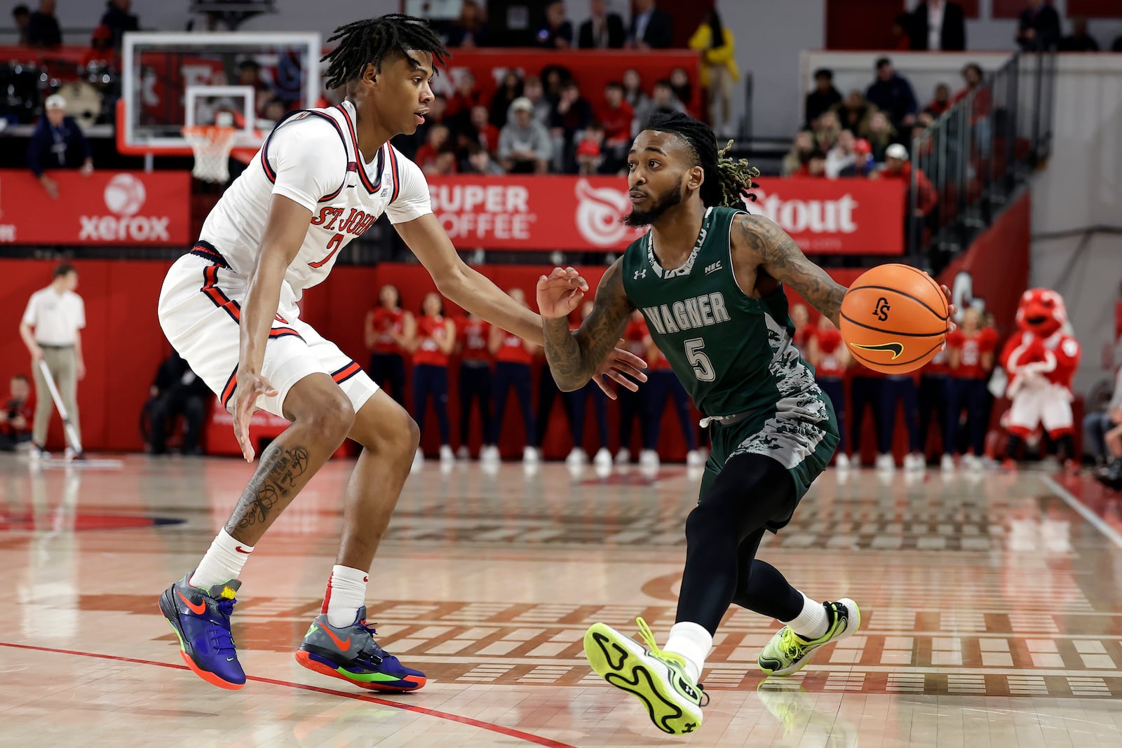 Wagner guard Zae Blake (5) passes around St. John's guard Simeon Wilcher during the first half of an NCAA college basketball game Wednesday, Nov. 13, 2024, in New York. (AP Photo/Adam Hunger)