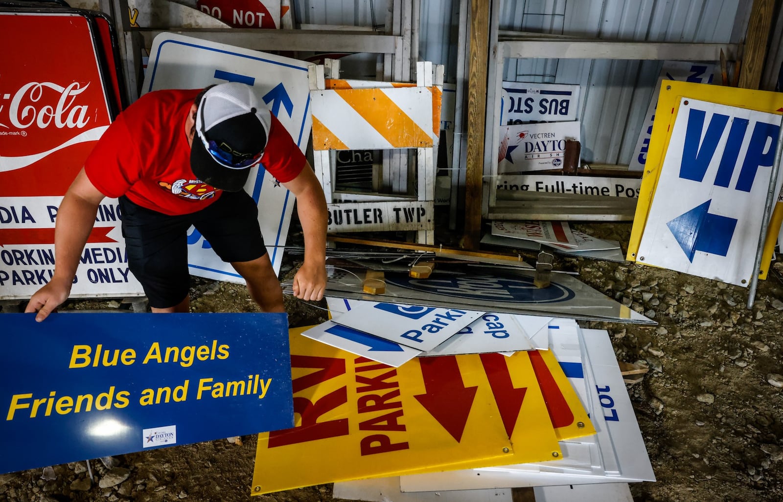 Dayton Air Show worker, Austin Lackey wades through a stack of air show sign that will direct the thousands of air show attendees this weekend. JIM NOELKER/STAFF