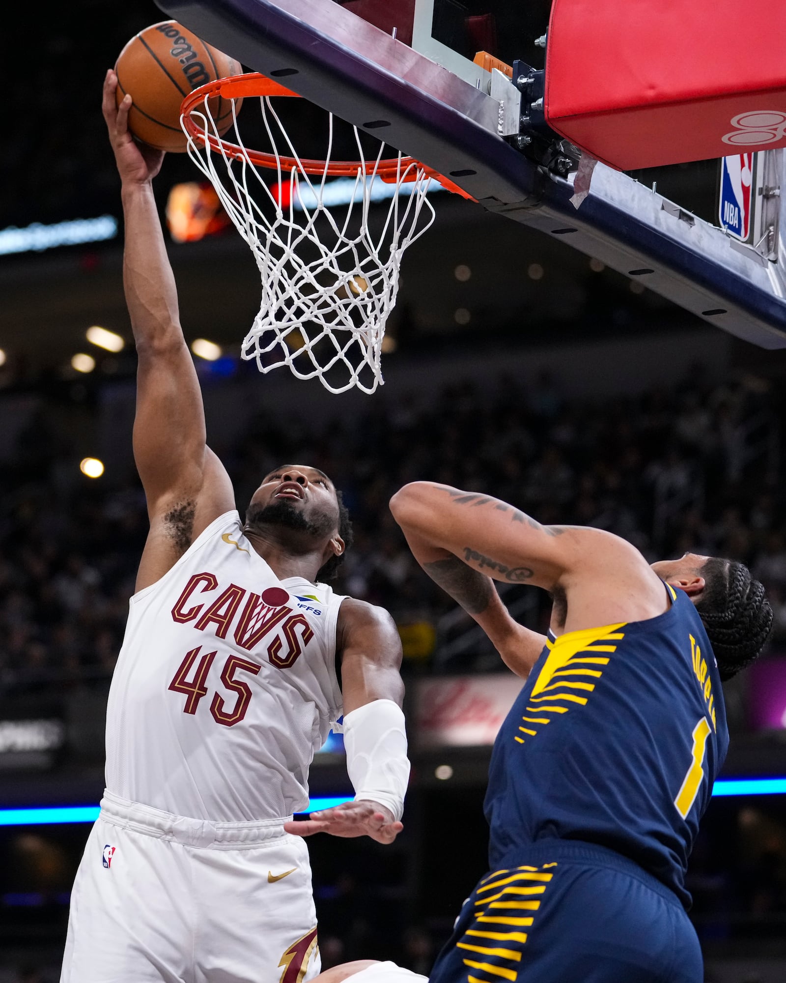 Cleveland Cavaliers guard Donovan Mitchell (45) tips in the ball over Indiana Pacers forward Obi Toppin (1) during the second half of an NBA basketball game in Indianapolis, Tuesday, Jan. 14, 2025. (AP Photo/Michael Conroy)