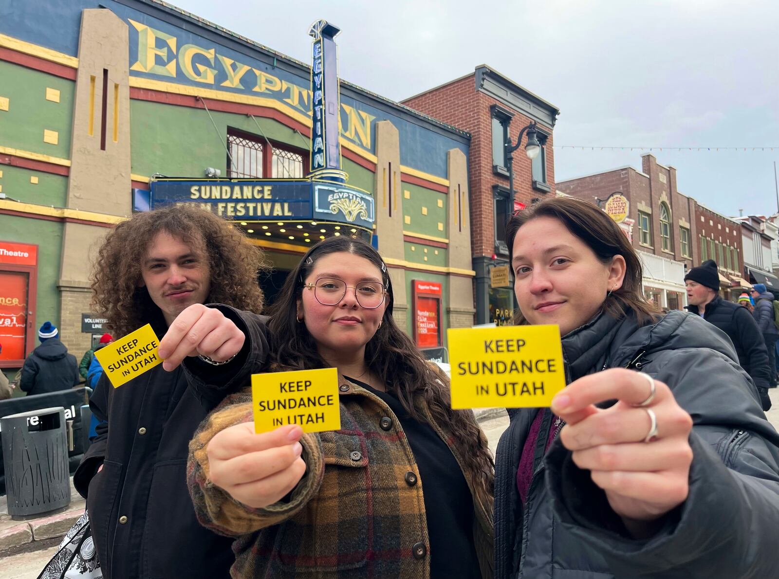 Attendees of the 2025 Sundance Film Festival hold up "Keep Sundance in Utah" stickers on Main Street in Park City, Utah, Friday, Jan. 24, 2025. (AP Photo/Hannah Schoenbaum)