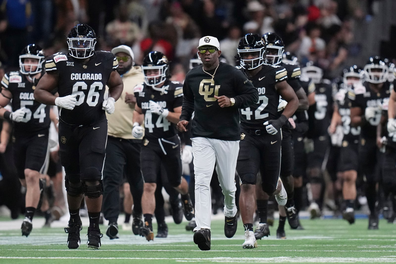 Colorado head coach Deion Sanders, center, takes the field with his team before the Alamo Bowl NCAA college football game against BYU, Saturday, Dec. 28, 2024, in San Antonio. (AP Photo/Eric Gay)