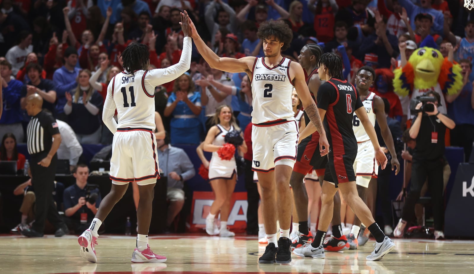 Dayton's Malachi Smith slaps hands with Nate Santos after a victory against Saint Joseph’s on Friday, Jan. 24, 2025, at UD Arena. David Jablonski/Staff