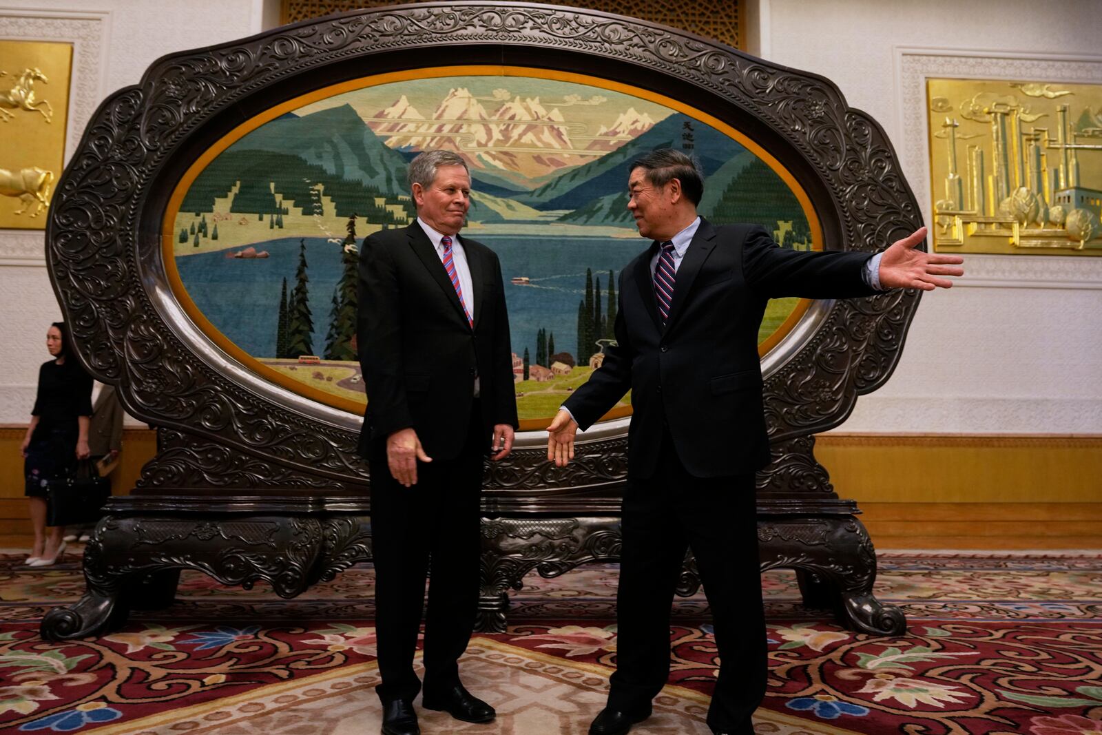 Chinese Vice Premier He Lifeng, right, shows the way for U.S. Sen. Steve Daines before a meeting held in the Xinjiang Room at the Great Hall of the People in Beijing, China, Saturday, March 22, 2025. (AP Photo/Ng Han Guan, Pool)