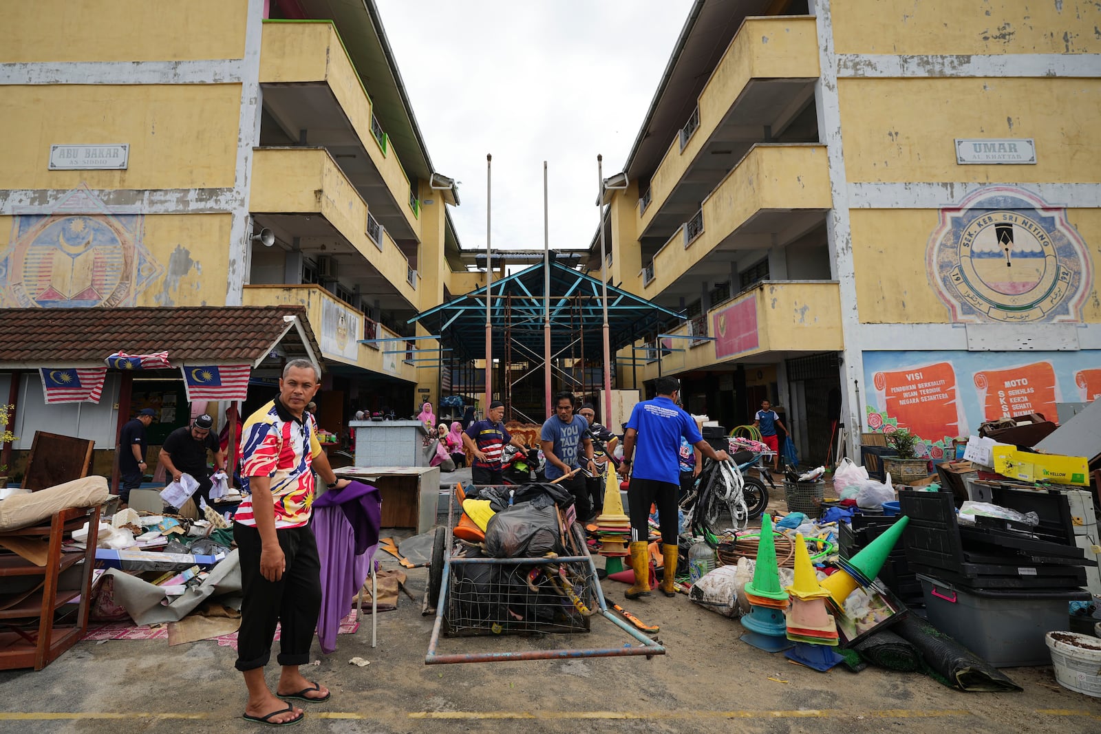 People remove items from a flooded school in Tumpat, on the outskirts of Kota Bahru, Malaysia, Tuesday, Dec. 3, 2024. (AP Photo/Vincent Thian)