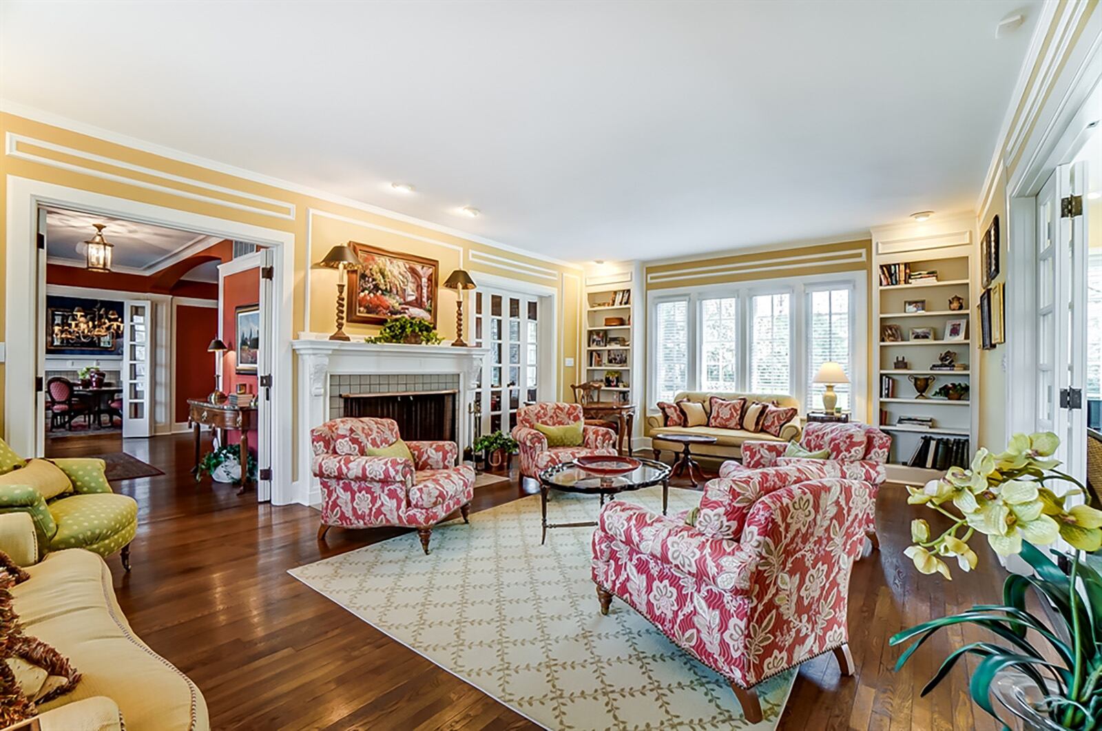 The living room is bright with front and rear windows. A fireplace has an ornate wood mantel, and there are built-in bookcases accented with lights. Hardwood flooring fills the room, and a second set of French doors opens into an adjoining sun room. CONTRIBUTED PHOTO