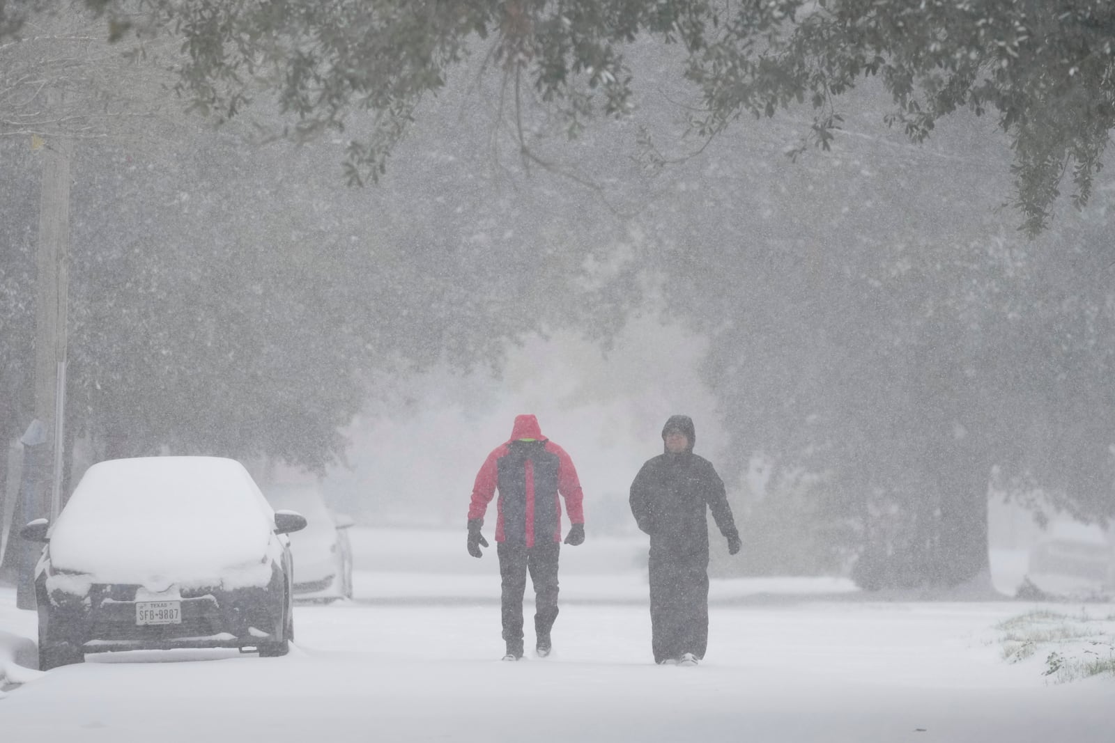 People take a walk in the neighborhood Tuesday, Jan. 21, 2025, in Houston. (AP Photo/Ashley Landis)