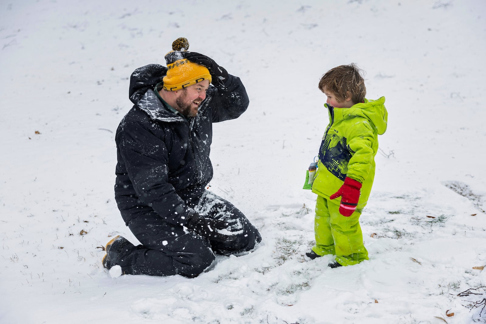 Stew Pollock adjusts his hat and smiles at his son, Roy Pollock, 2, while they play in the snow at Byrd Park, Wednesday, Feb. 19, 2025, in Richmond, Va. (Margo Wagner/Richmond Times-Dispatch via AP)