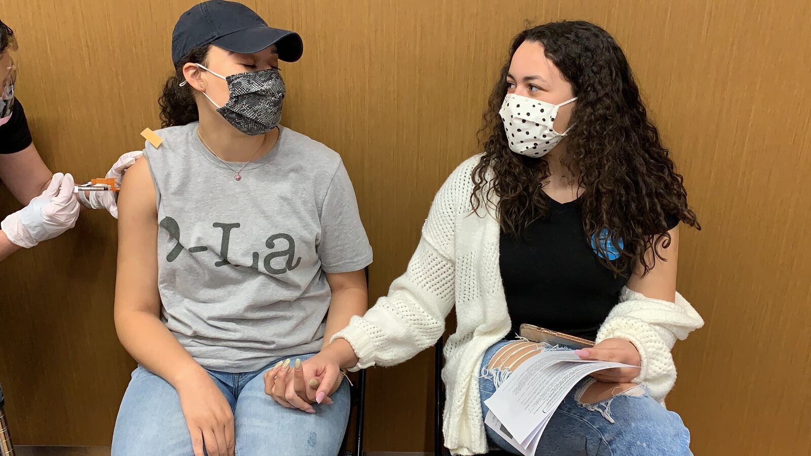 While she got her shot, Chloe Heard, 20, closed her eyes and squeezed her 16-year-old sister Camille Heard’s hand.