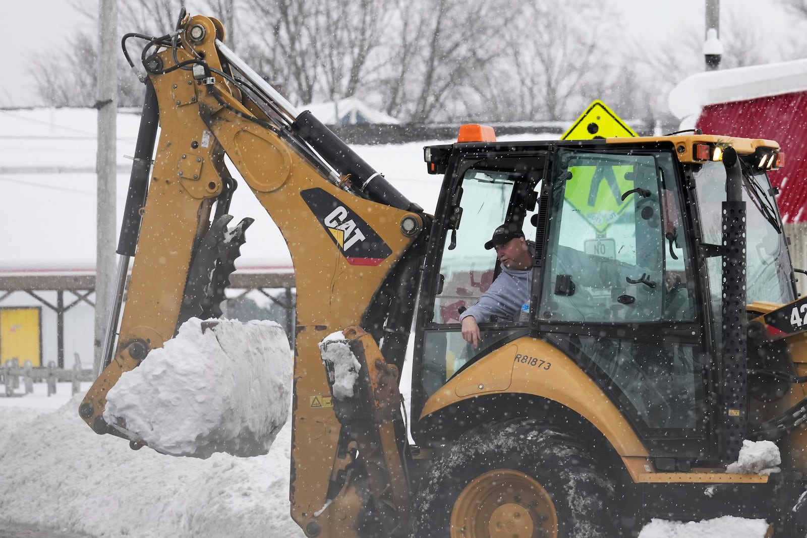 Dwayne Bennett, mayor of Geneva-on-the-Lake, drives a heavy equipment to clear snow as more snow falls Monday, Dec. 2, 2024, in Geneva-on-the-Lake, Ohio. (AP Photo/Sue Ogrocki)