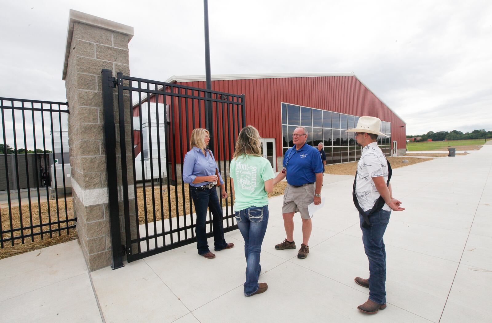 Fair board President John Yancik, second from right, talks to people Monday at the entrance gate of the new Montgomery County Fairgrounds & Expo Center in Jefferson Twp. Behind the group is the 26,000-square-foot main event building. CHRIS STEWART / STAFF