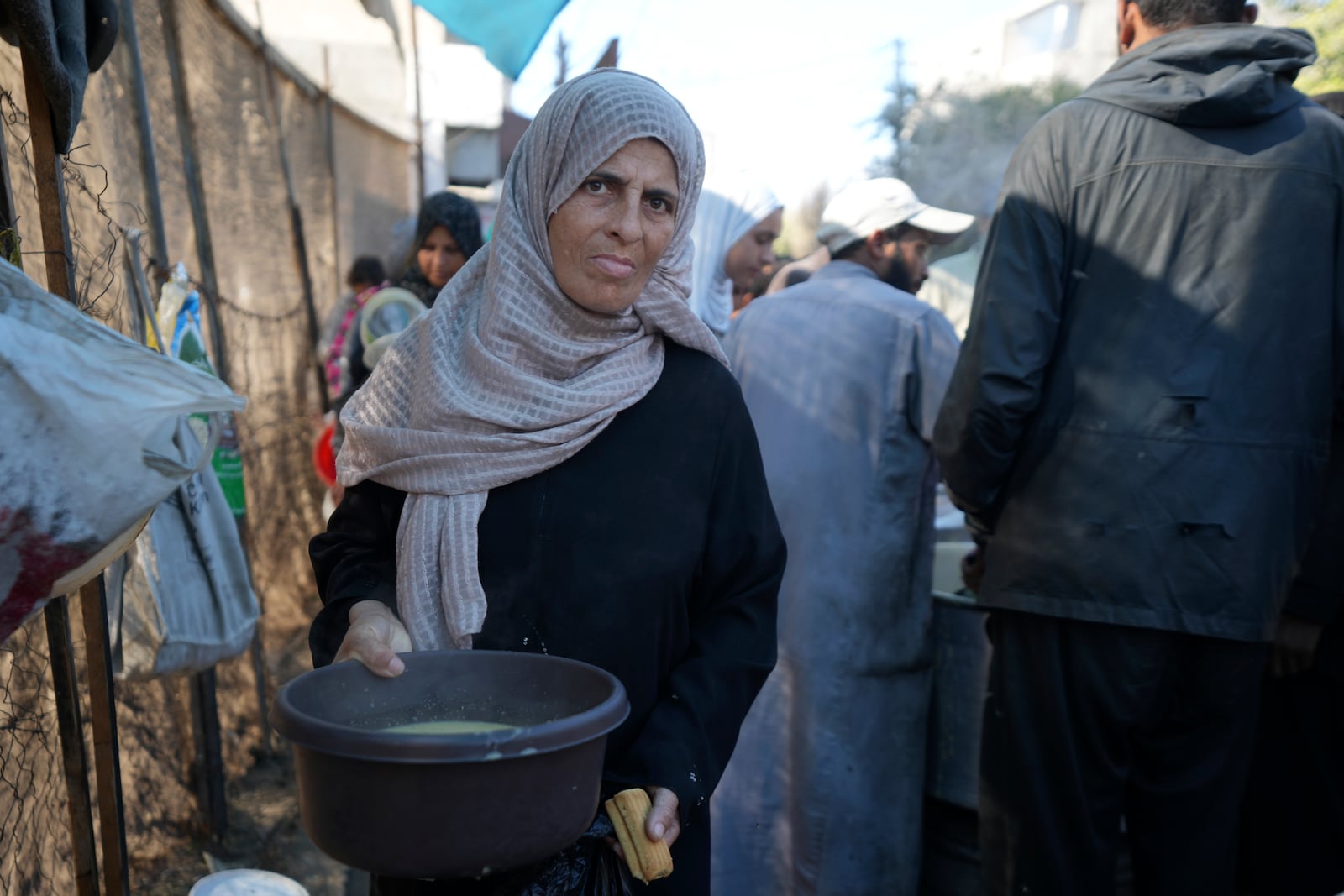 A Palestinian woman queues for food in Deir al-Balah, Gaza Strip, Monday, Nov. 18, 2024. (AP Photo/Abdel Kareem Hana)