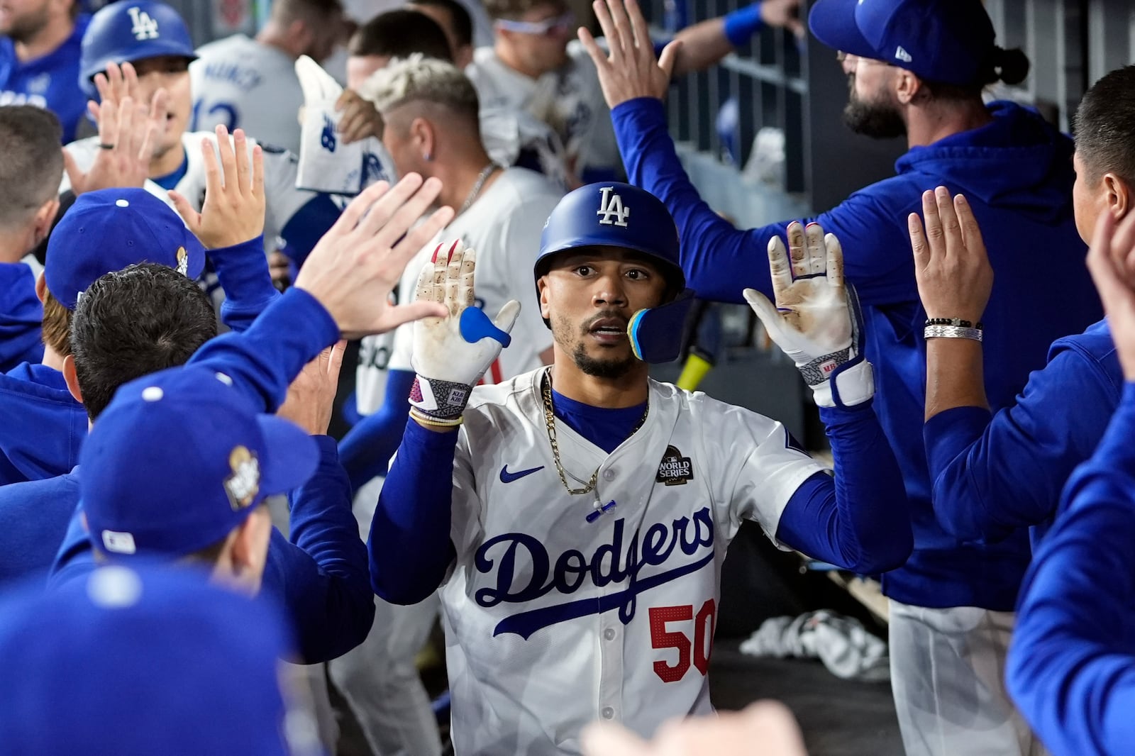 Los Angeles Dodgers' Mookie Betts (50) celebrates in the dugout after hitting a sacrifice fly against the New York Yankees during the eighth inning in Game 1 of the baseball World Series, Friday, Oct. 25, 2024, in Los Angeles. (AP Photo/Godofredo A. Vásquez)