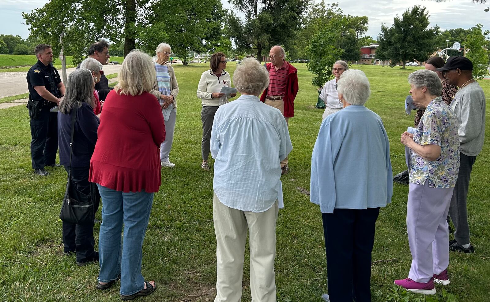 Two Dayton police officers join a group of Dayton-area residents holding a prayer vigil for homicide victims June 8, 2024, at McIntosh/Riverview Park in Dayton. JEREMY P. KELLEY / STAFF