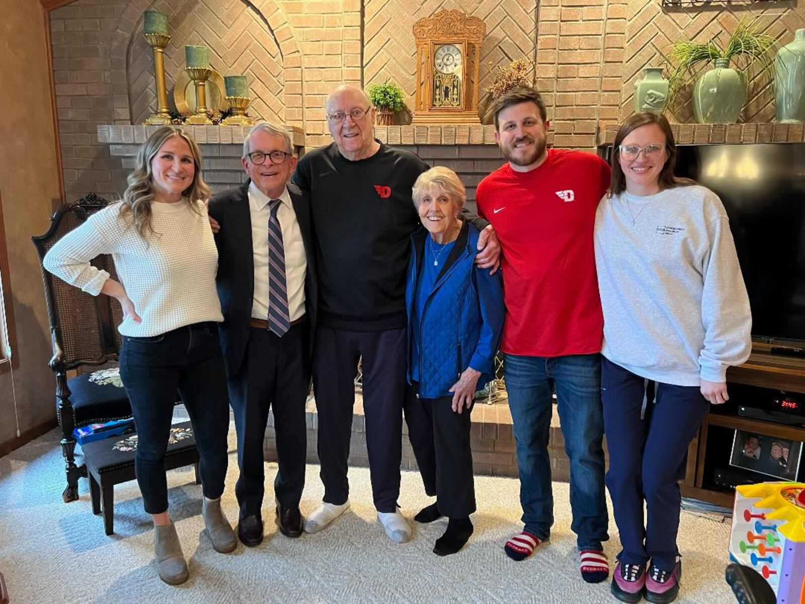 Ohio Governor Mike DeWine grew up a Dayton Flyers fan. As an eight-year-old boy in Yellow Springs, he kept a scrapbook of the 1955-56 Flyers team where Bockhorn was one of the stars alongside guys like Bill Uhl, Jim Paxson  and Jim Palmer. Nine days ago DeWine visited Bockhorn and his wife Peggy at their Bellbrook home and gave the UD legend a copy of the scrapbook. Three Bockhorn grandchildren joined the get together. (Pictured left to right): Emma Bockhorn, Gov, Mike DeWine, Bucky, Peggy, Brad Bockhorn and Laura Scheper. CONTRIBUTED