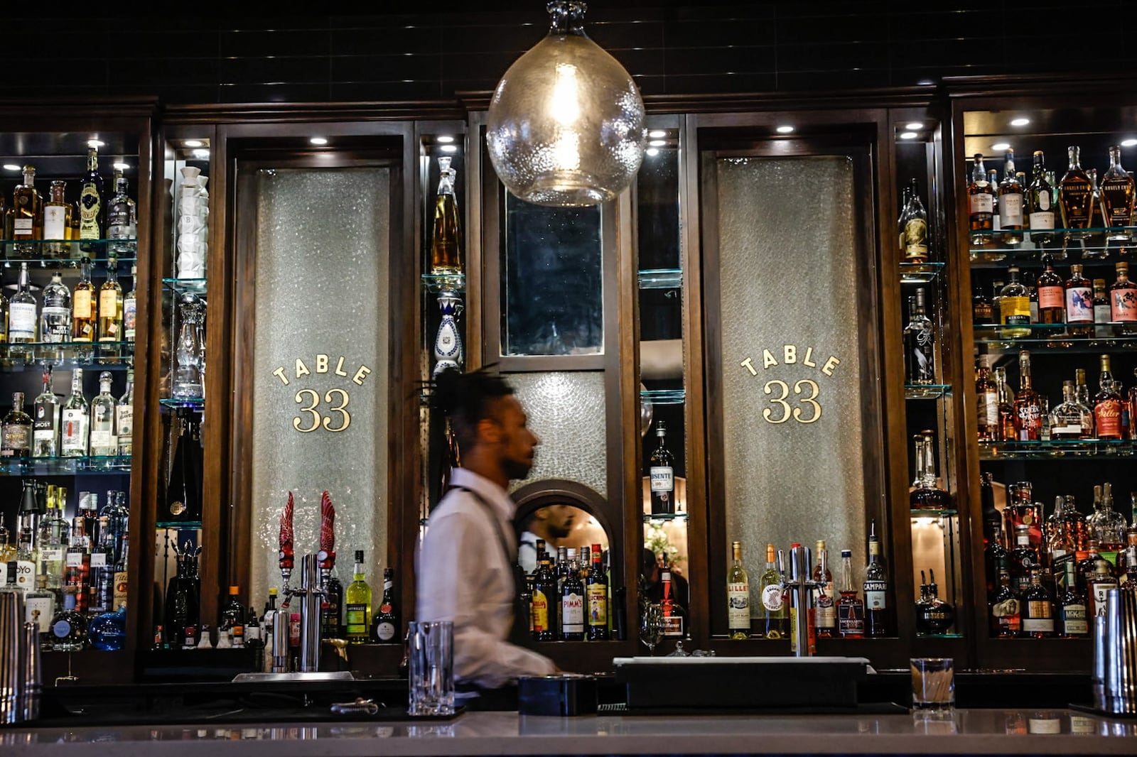 Table 33 barkeep Jalen Cambell walks through the bar at the restaurants new location at the Dayton Arcade. JIM NOELKER/STAFF