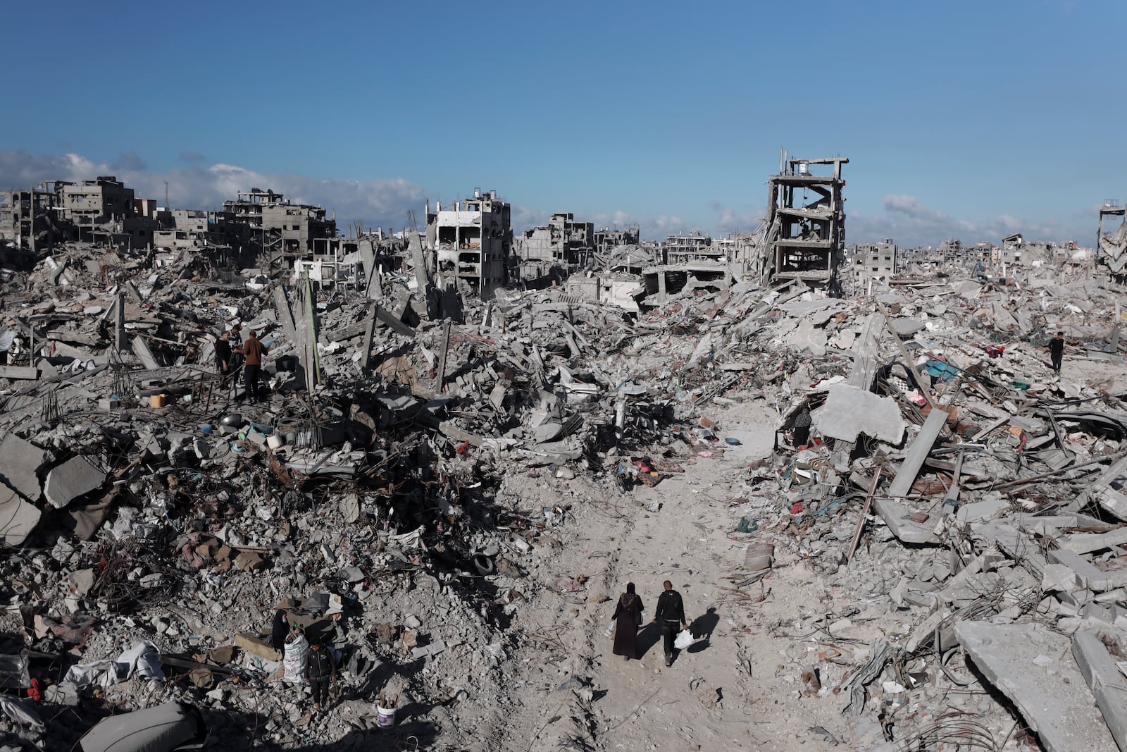 Palestinians walk through the destruction caused by the Israeli air and ground offensive in Jabaliya, a day after the ceasefire deal between Israel and Hamas came into effect, Monday, Jan. 20, 2025. (AP Photo/Abed Hajjar)