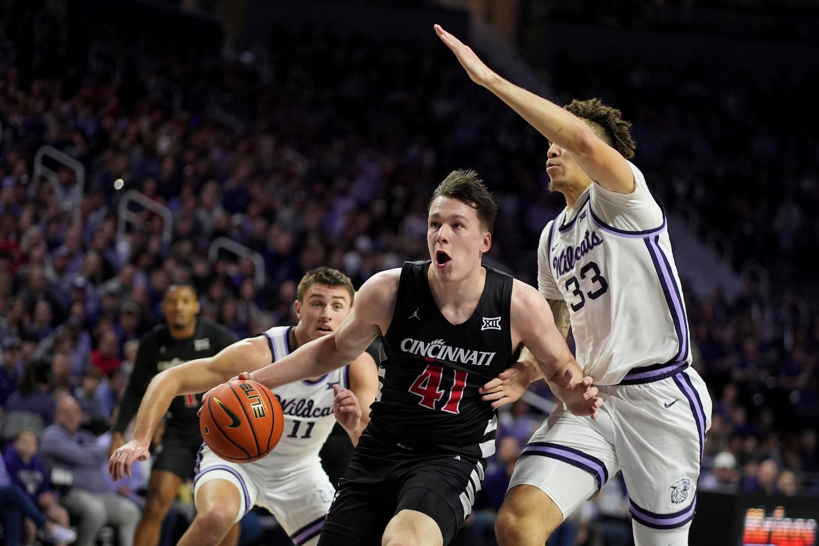 Cincinnati guard Simas Lukosius (41) drives past Kansas State guard Coleman Hawkins (33) during the first half of an NCAA college basketball game, Monday, Dec. 30, 2024, in Manhattan, Kan. (AP Photo/Charlie Riedel)