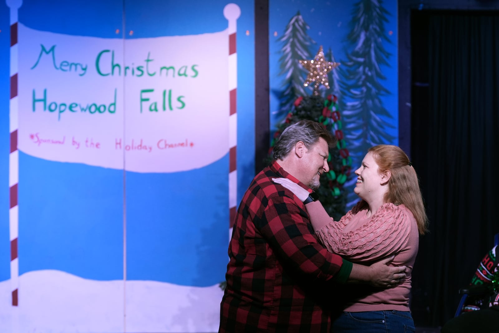 Rebecca Ulbrich, right, and Howie Johnson embrace during a dress rehearsal for the production of "The Holiday Channel Christmas Movie Wonderthon" at the Ghostlight Theatre in Sun City West, Ariz., on Dec. 9, 2024. (AP Photo/Ross D. Franklin)