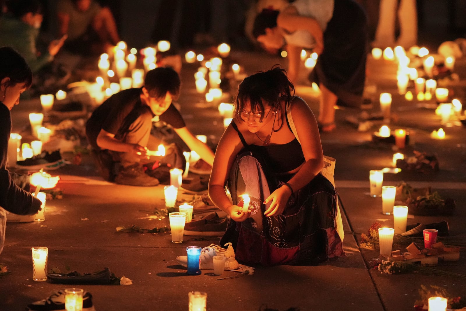 Demonstrators light candles at the Zocalo, Mexico City's main square, Saturday, March 15, 2025, as they hold a vigil for victims whose skeletal remains were discovered at a ranch in Jalisco state. (AP Photo/Eduardo Verdugo)