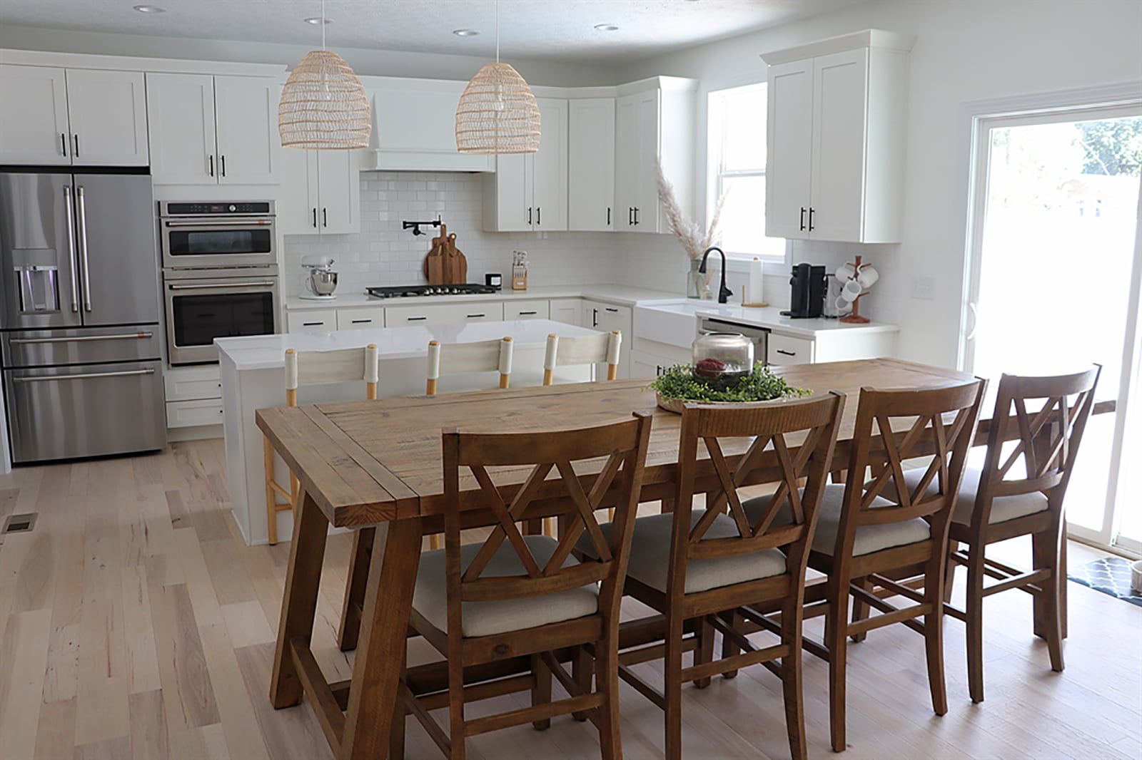 White shaker cabinetry fills two walls and is complemented by white quartz countertops. A window is above the extended farm sink, and a pot-filler faucet enhances the gas cooktop. White subway tile fills the wall space between countertops and hanging cabinets. CONTRIBUTED PHOTO BY KATHY TYLER