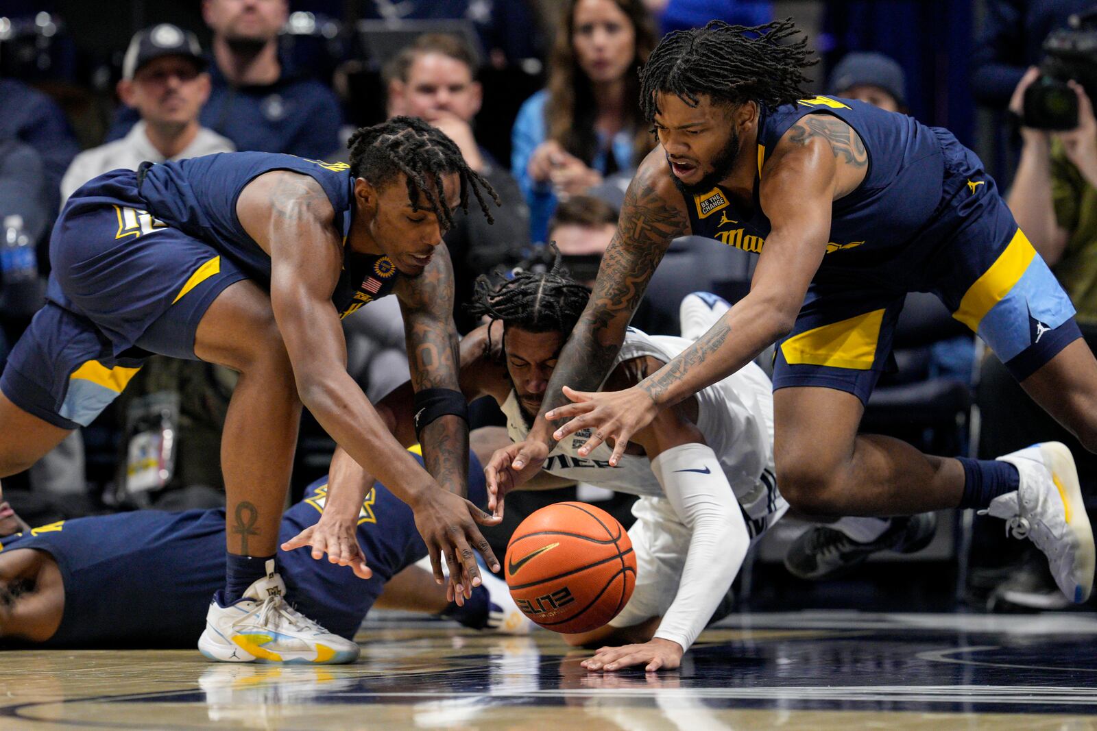 Marquette's Tre Norman, left, dives for a loose ball with teammate David Joplin, right, against Xavier's Jerome Hunter, center, during the first half of an NCAA college basketball game, Saturday, Dec. 21, 2024, in Cincinnati. (AP Photo/Jeff Dean)