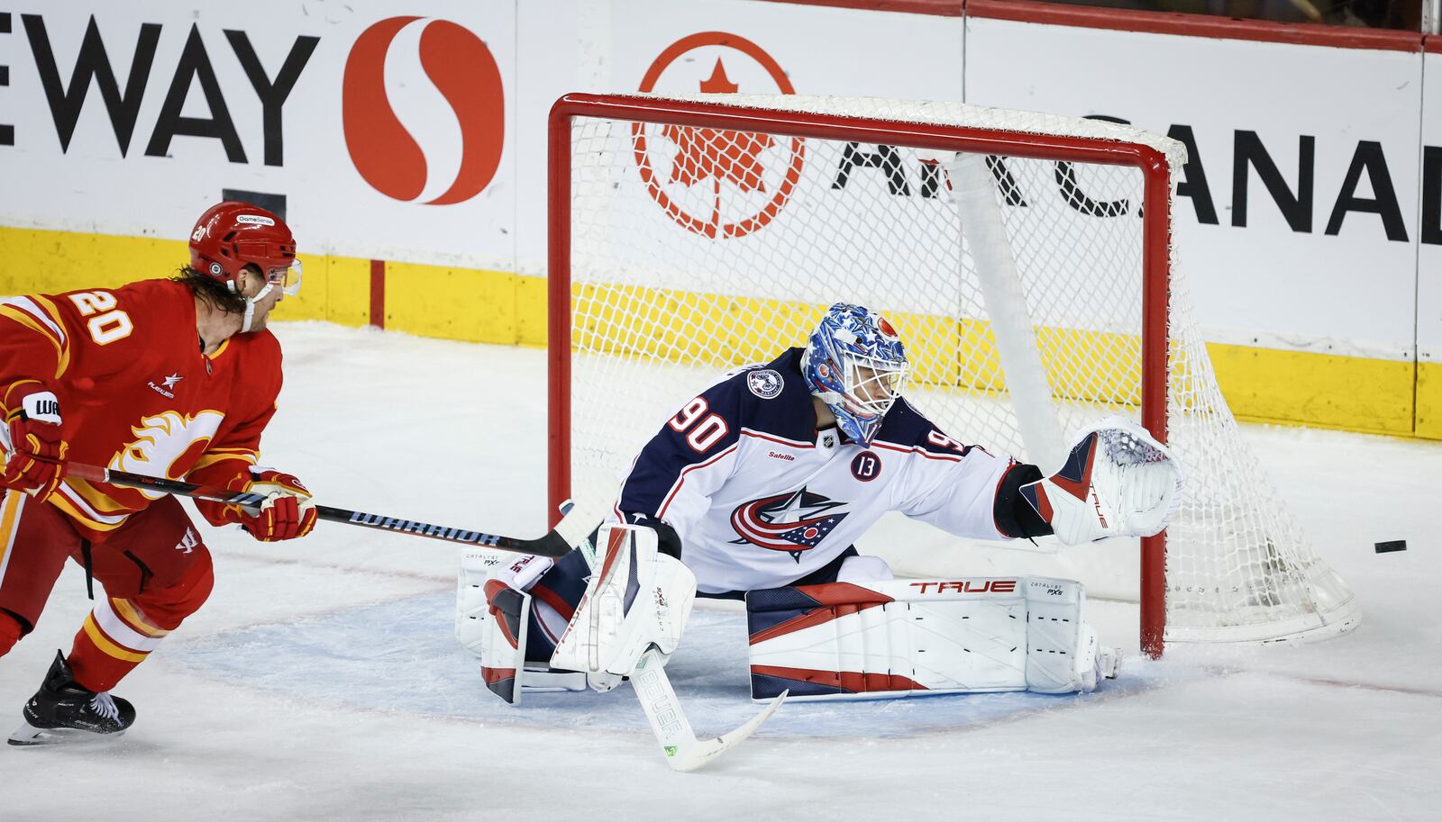 Columbus Blue Jackets goalie Elvis Merzlikins, right, reaches for shot from Calgary Flames' Blake Coleman during second period NHL hockey action in Calgary on Tuesday, Dec. 3, 2024. (Jeff McIntosh/The Canadian Press via AP)