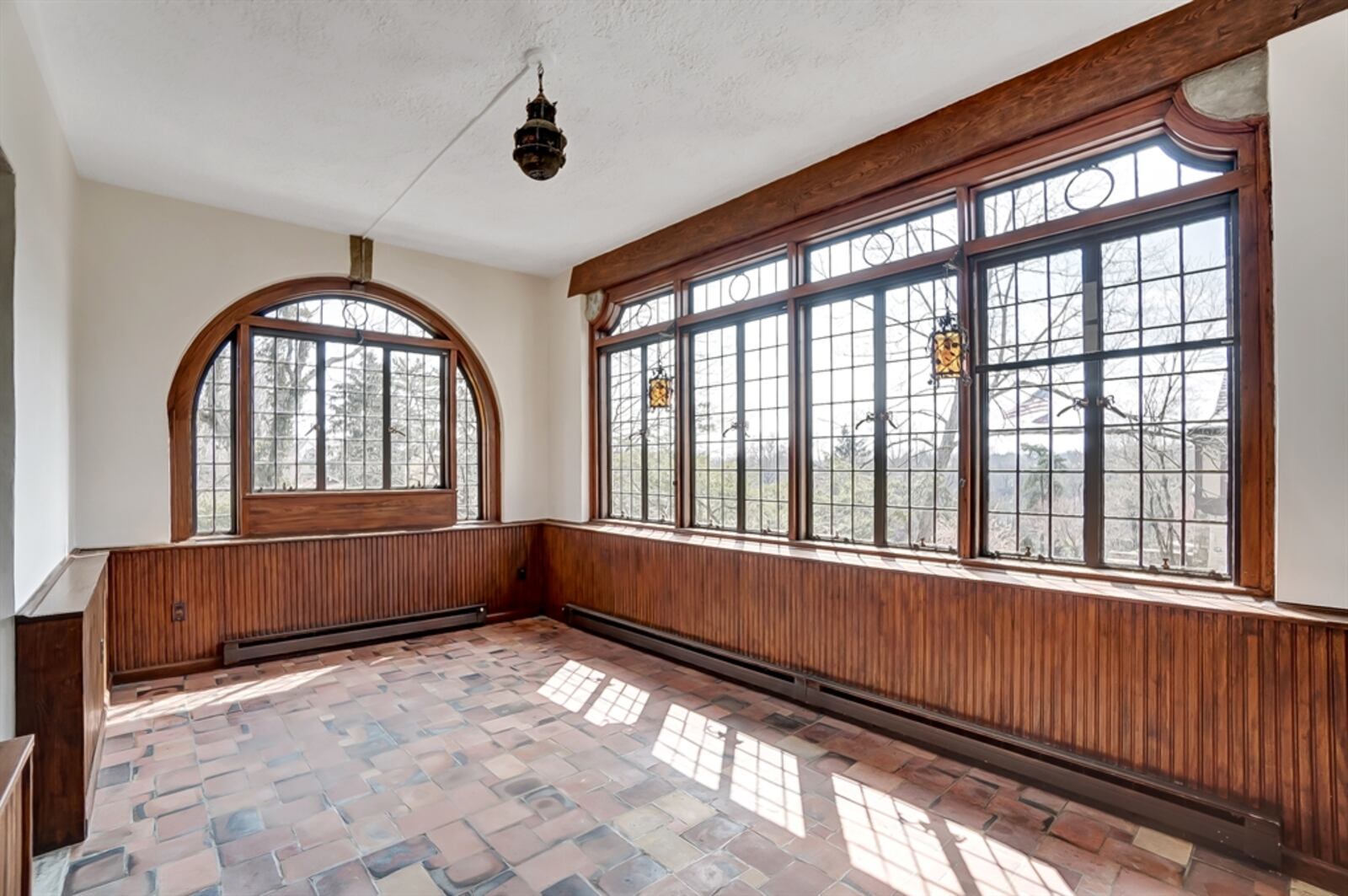 French doors open out to the Rookwood sunroom. Distressed brick flooring complements the Rookwood details, and a keystone accents the arched window and patio doors.