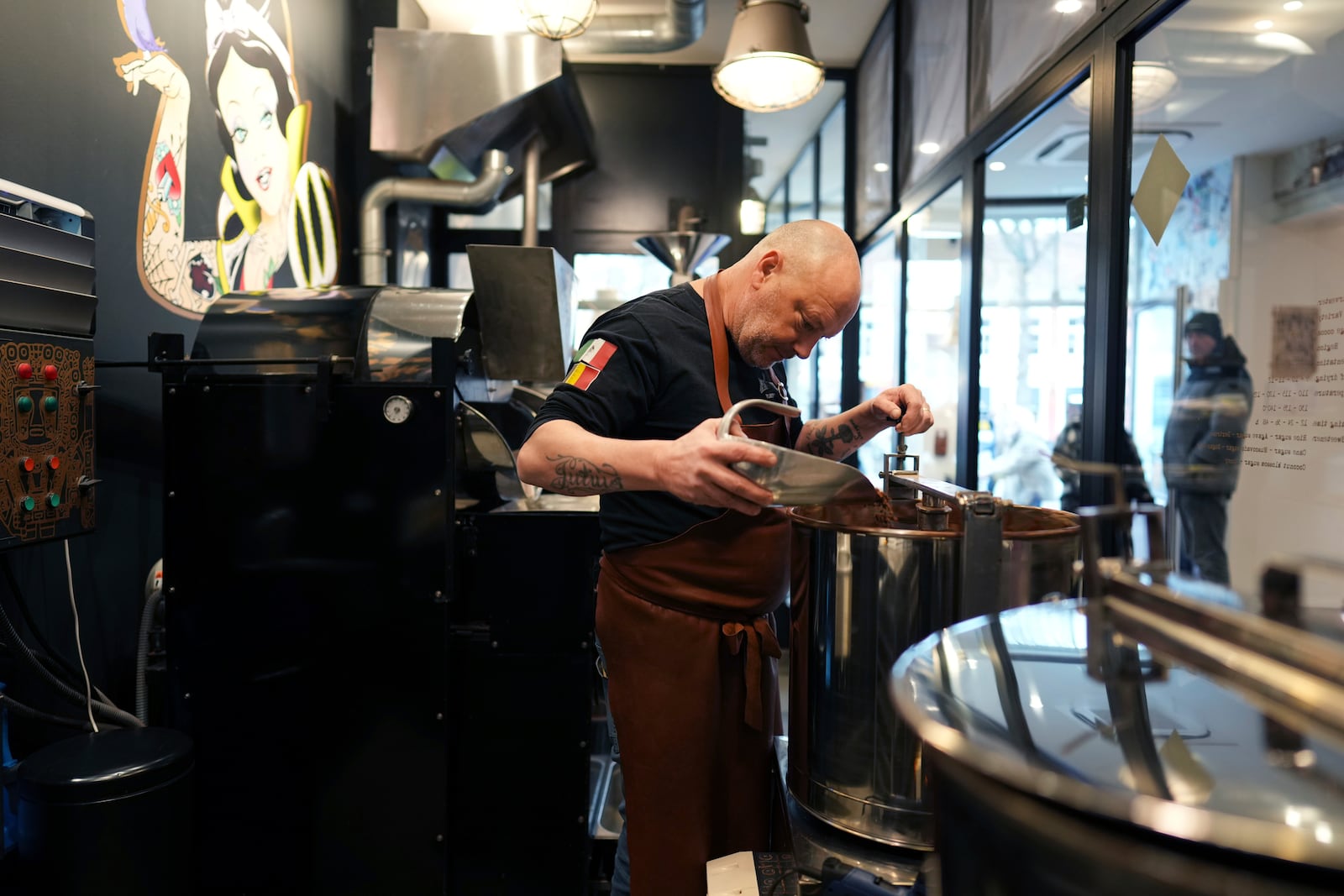 Artisan chocolatier Dominique Persoone pours cocoa beans in a machine in his workshop at The Chocolate Line in Bruges, Belgium, Thursday, Feb. 6, 2025. (AP Photo/Virginia Mayo)