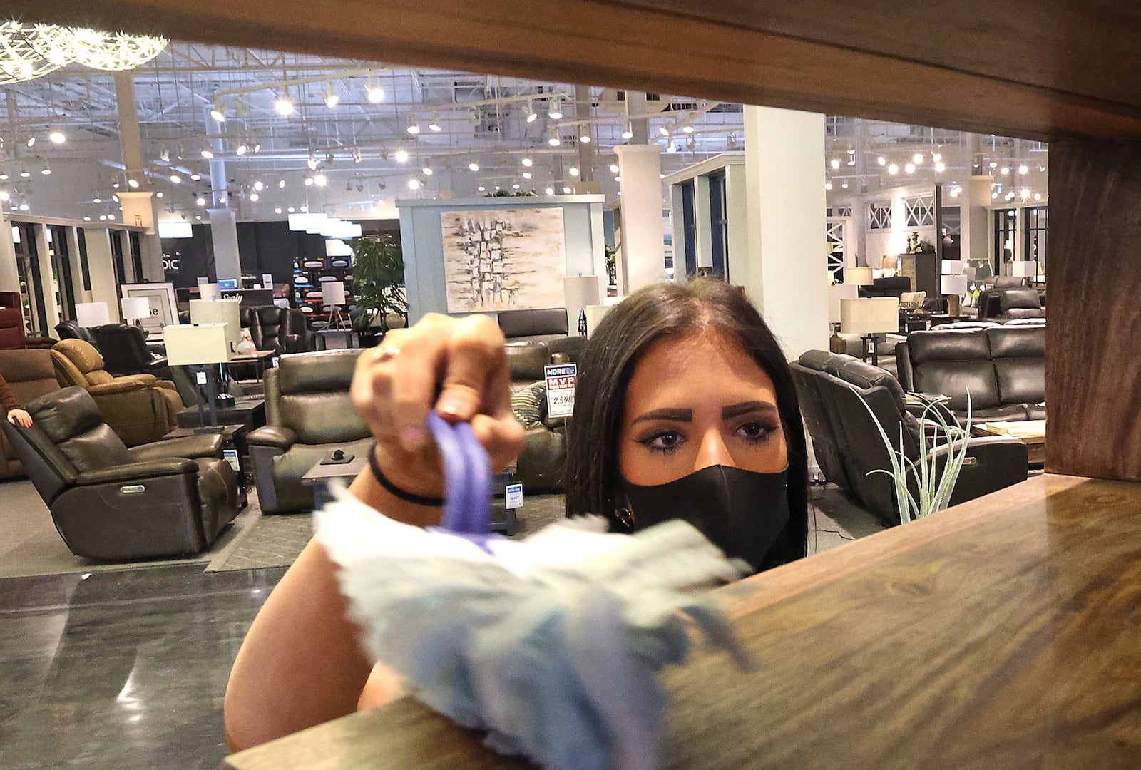 Morris Home Furniture sales professional Kayla Gregg dusts dusts some of the items in the showroom between customers Friday at Morris' Beavercreek store. BILL LACKEY/STAFF