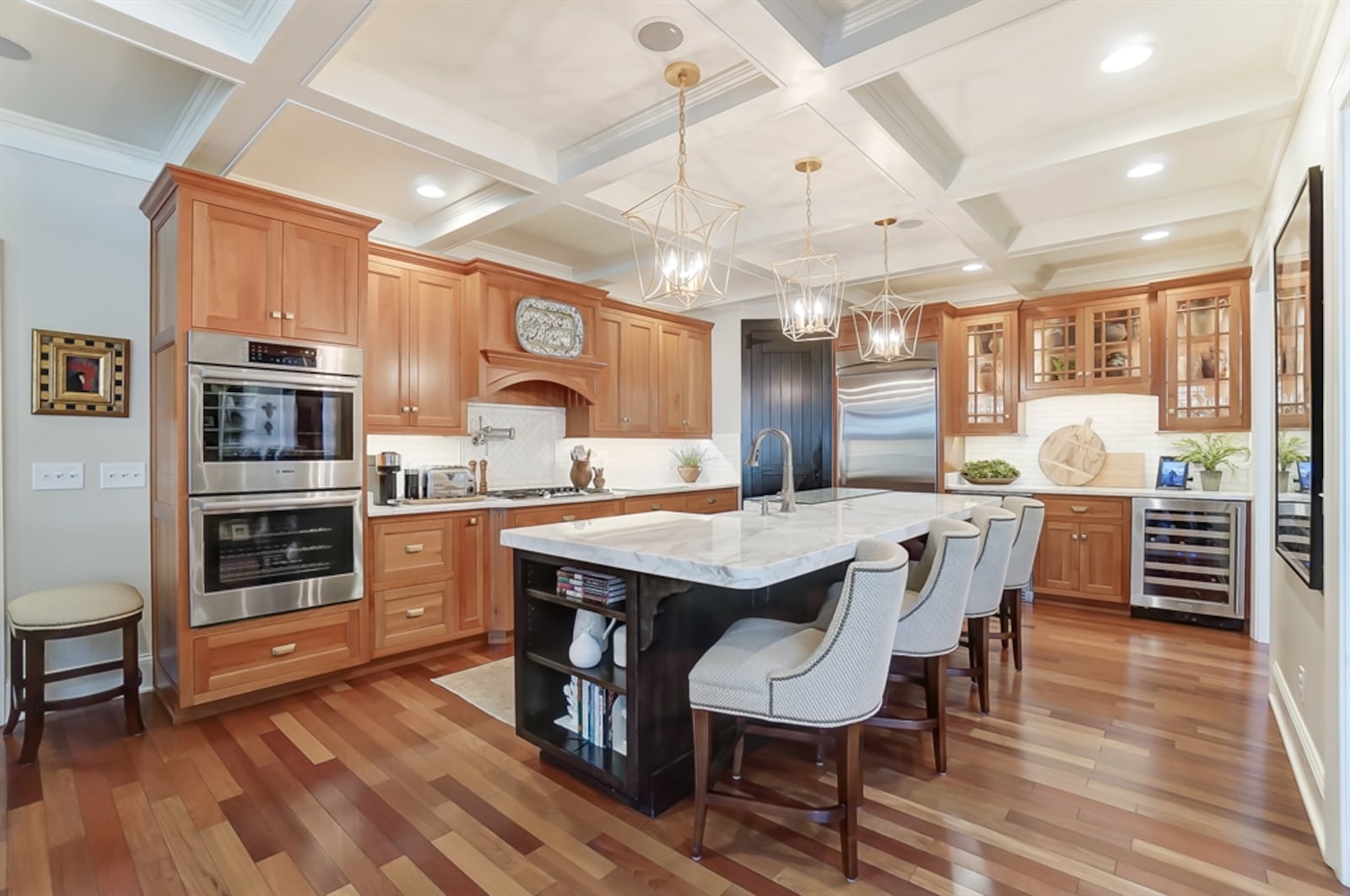 In the kitchen, open shelves accent each end of the island, and the extended counter allows for seating up to six. Hickory cabinetry surrounds stainless-steel appliances.