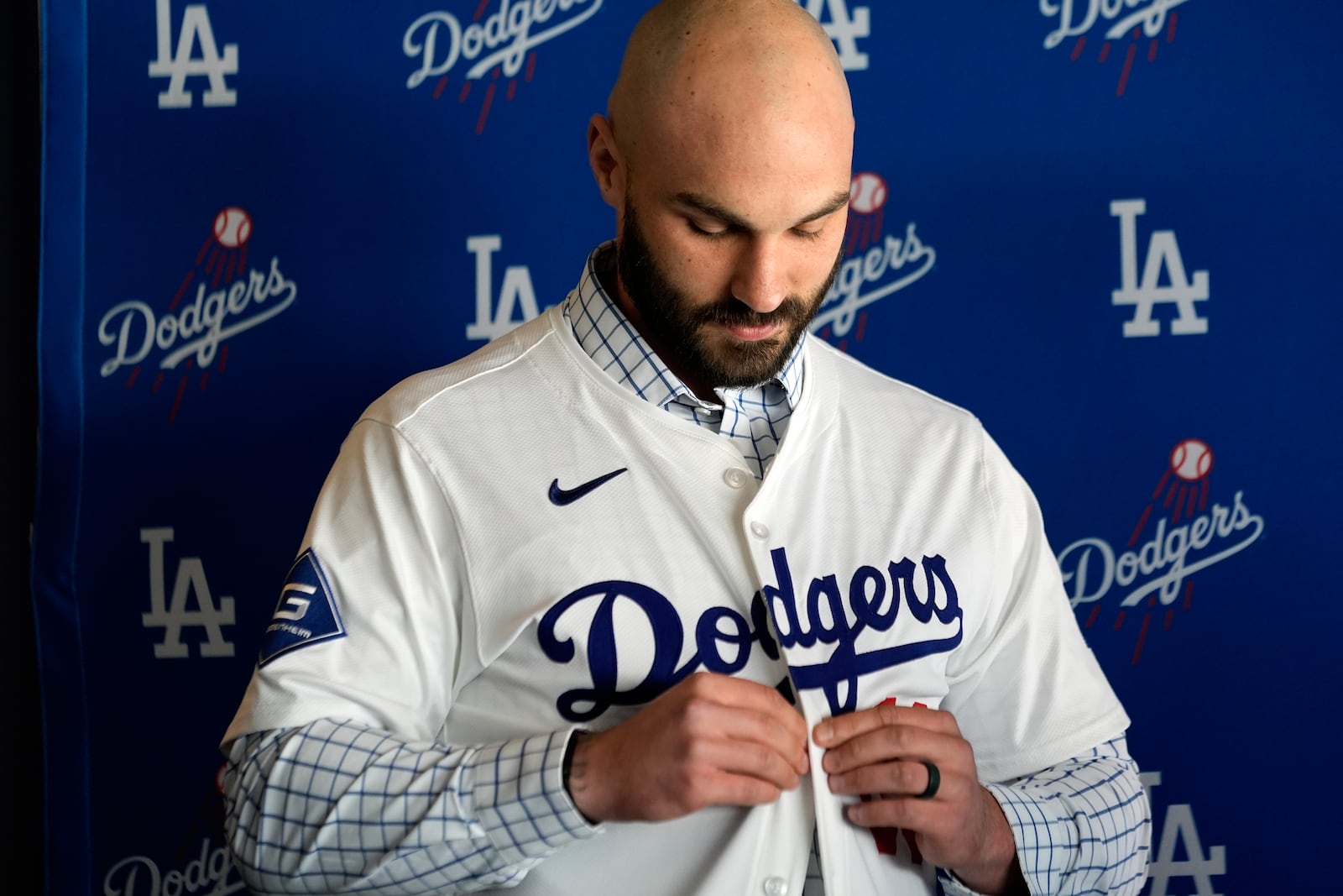 Left-handed reliever Tanner Scott buttons up his new Los Angeles Dodgers jersey at an introduction news conference at Dodger Stadium in Los Angeles on Thursday, Jan. 23, 2025. (AP Photo/Richard Vogel)