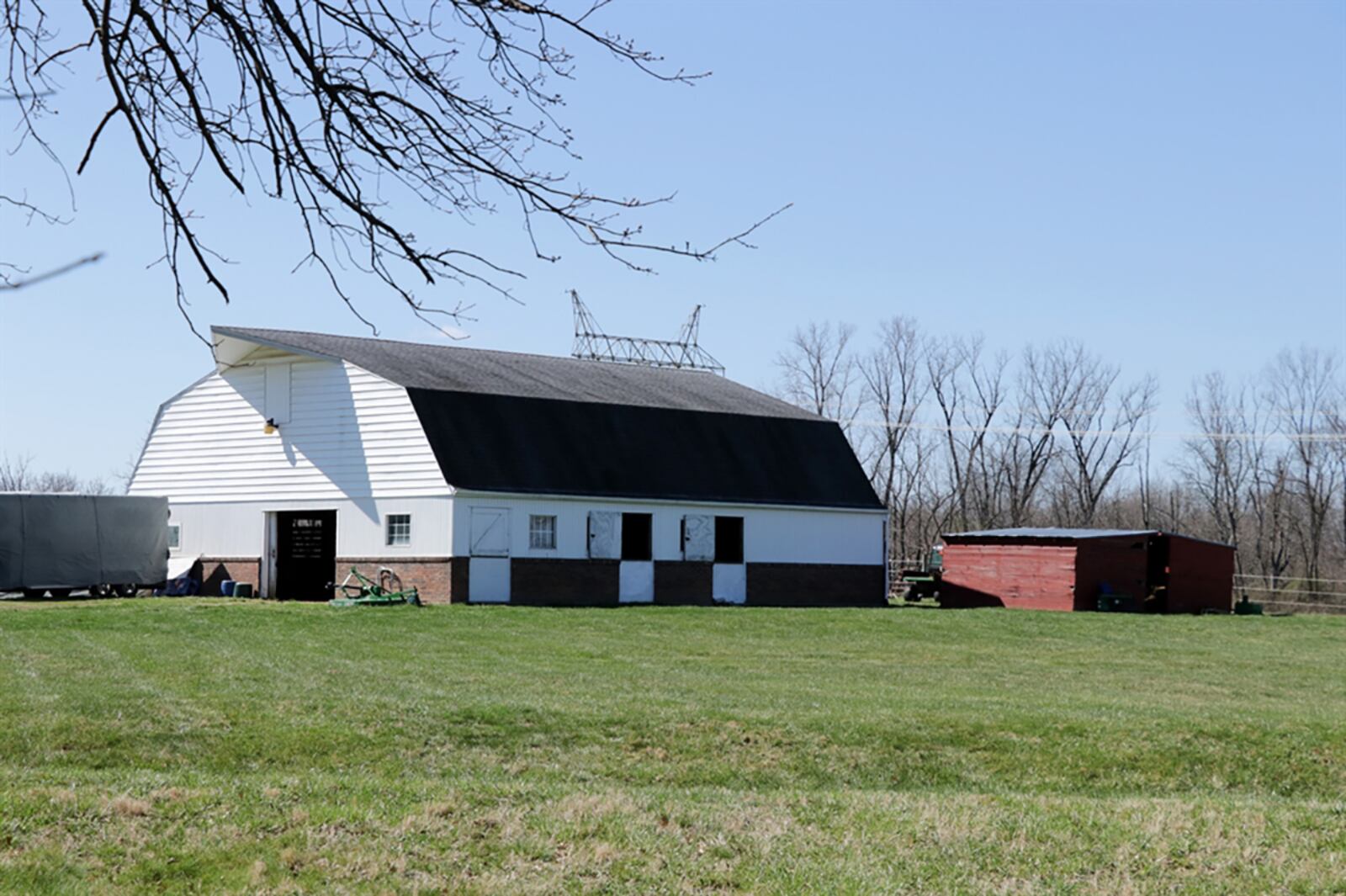 The gothic arched-roof barn has a hayloft door cover and red brick accents near the foundation and white wood plank walls. CONTRIBUTED PHOTO BY KATHY TYLER