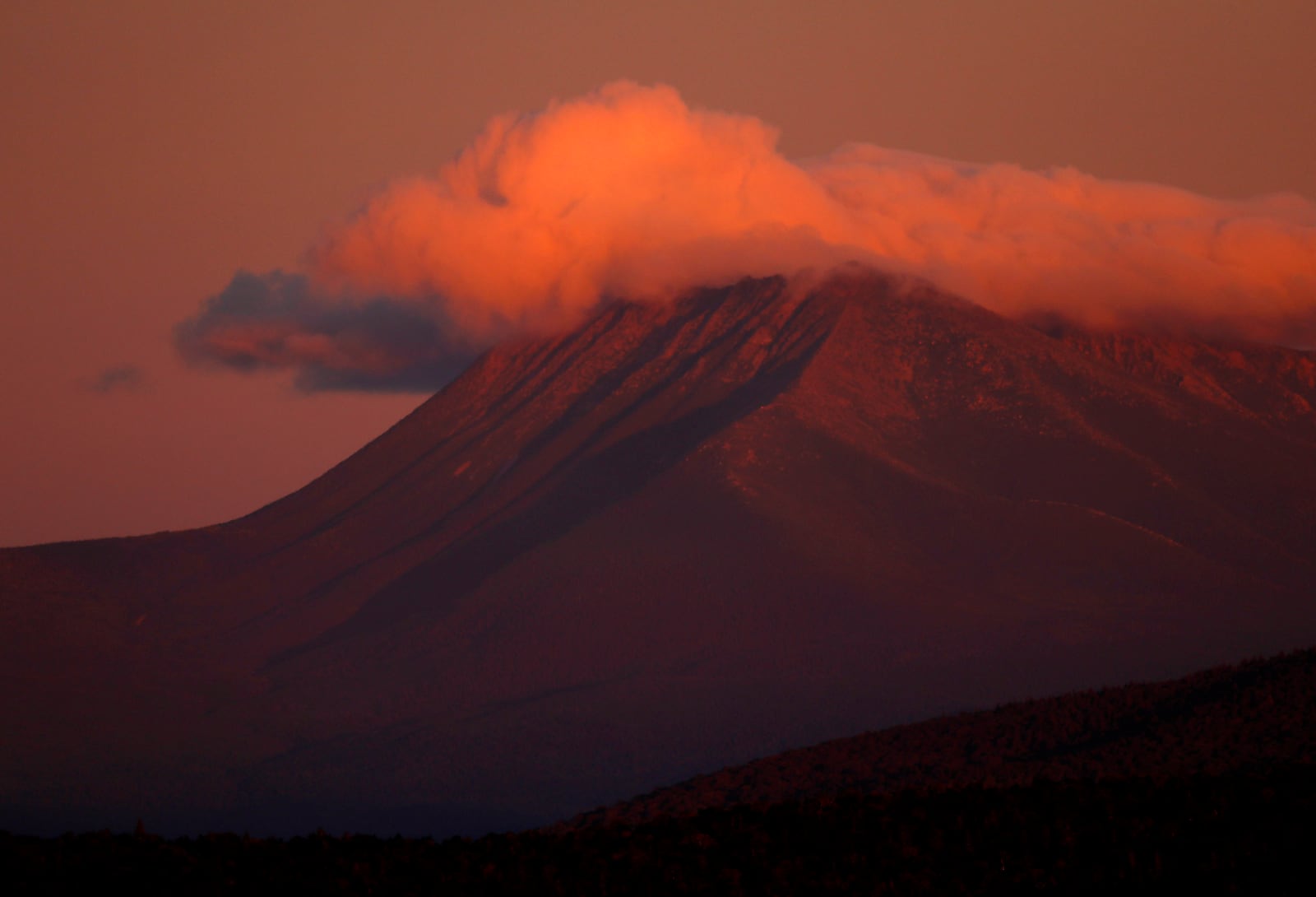 FILE - In this Aug. 7, 2017, file photo, the first rays of sunlight color the clouds over Mount Katahdin in this view from Patten, Maine. (AP Photo/Robert F. Bukaty, File)