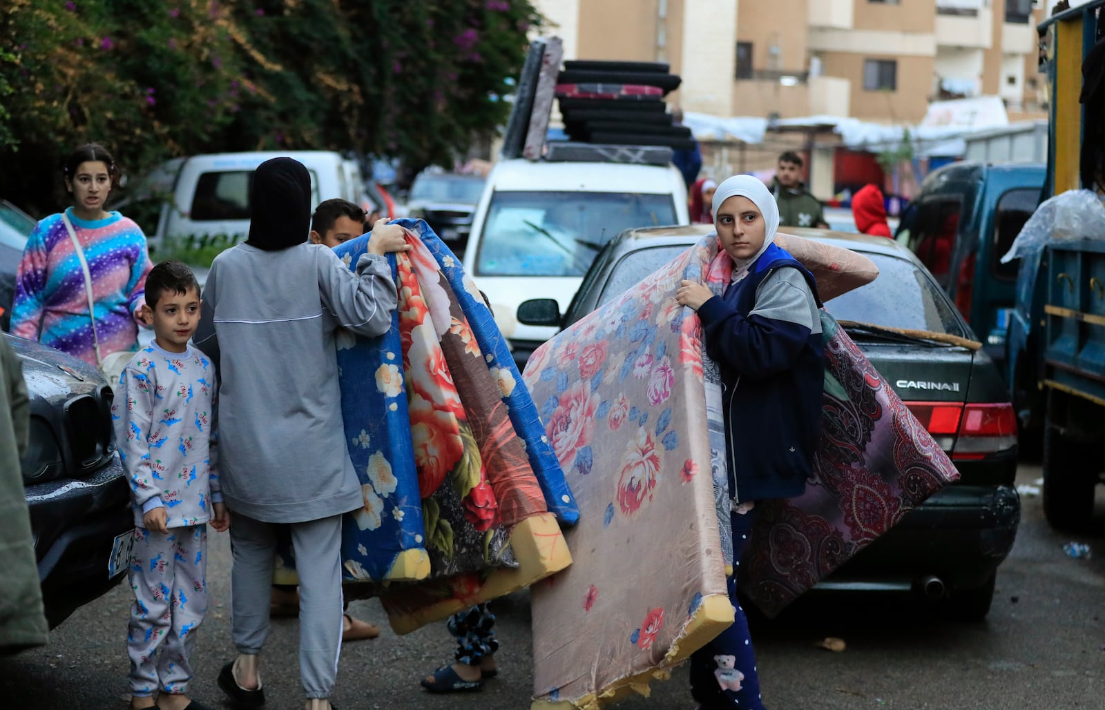 Displaced families carry mattresses as they prepare to return to their villages after a ceasefire between Israel and Hezbollah went into effect in Sidon, Lebanon, Wednesday, Nov. 27, 2024. (AP Photo/Mohammed Zaatari)