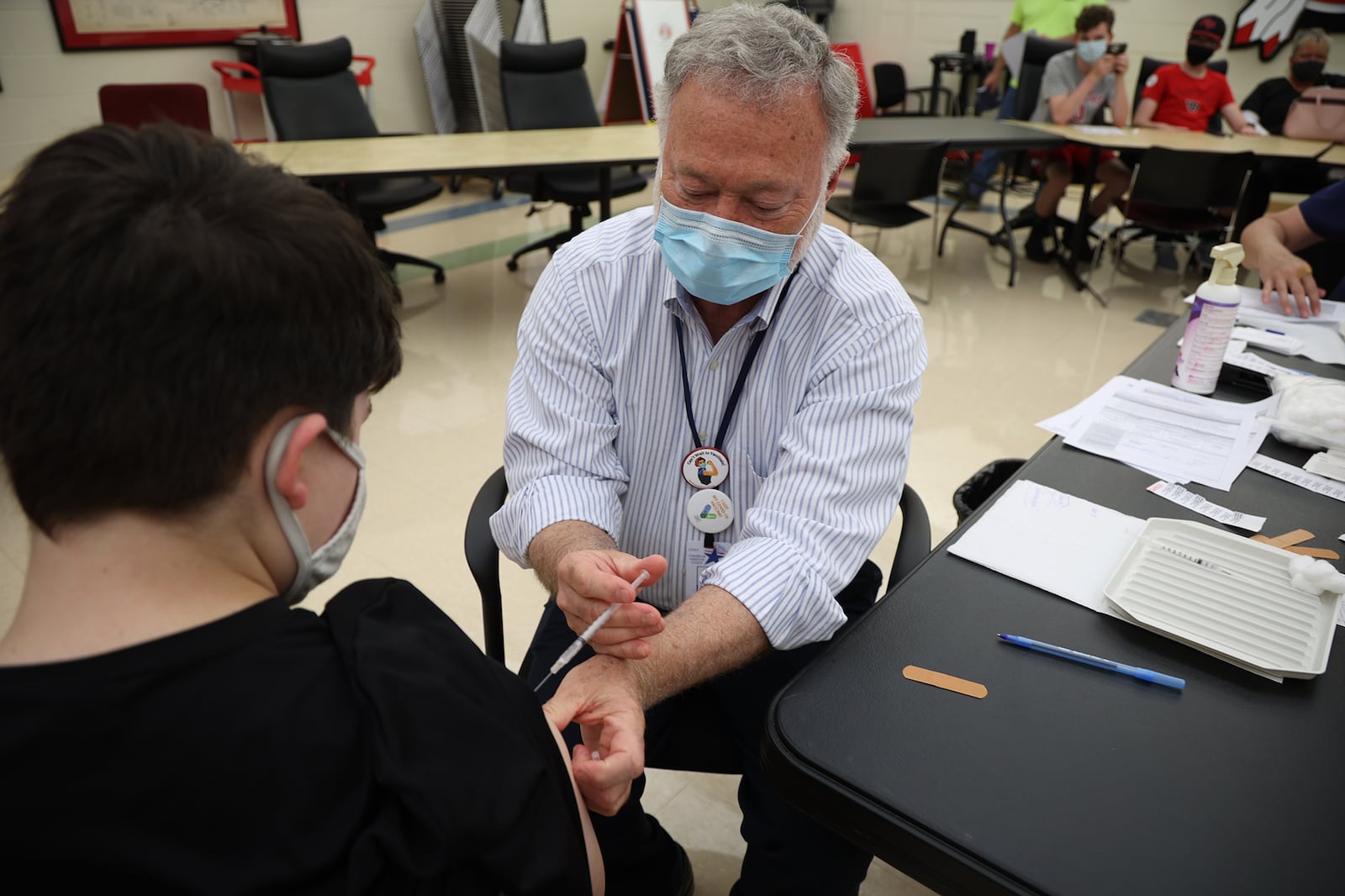 Dr. John Dobson gives Carsen Williams, 13, his COVID vaccination Wednesday during the COVID clinic at Tecumseh High School. BILL LACKEY/STAFF