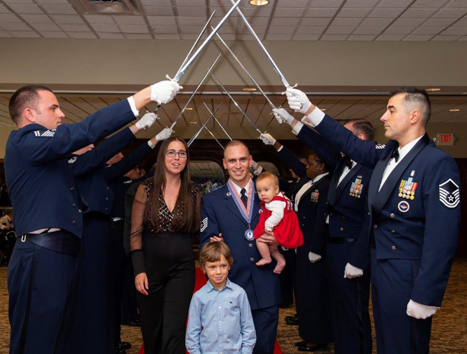 Tech. Sgt. Alexander Moyo, Air Force Institute of Technology, and his family pass through the sword cordon during the start of the senior NCO induction ceremony Aug. 26 at Wright-Patterson Air Force Base. U.S. AIR FORCE PHOTO/R.J. ORIEZ