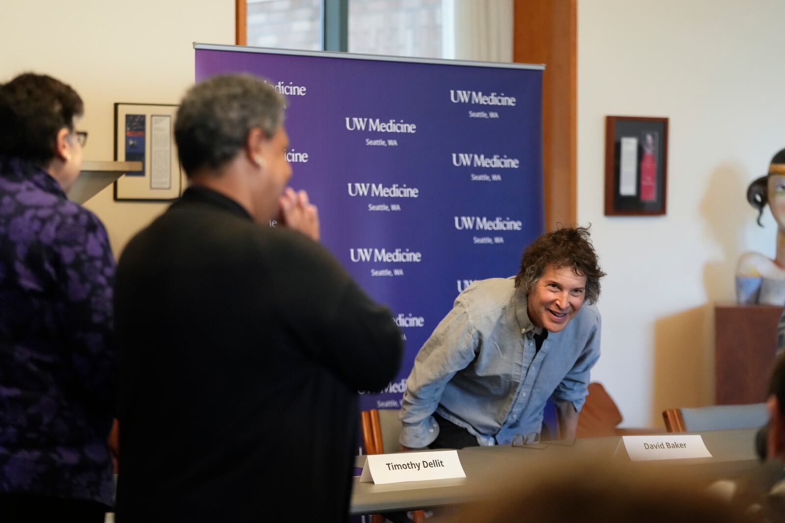 American biochemist David Baker, 2024 Nobel Prize winner in Chemistry, takes his seat before a news conference at the University of Washington on Wednesday, Oct. 9, 2024, in Seattle. University of Washington president Ana Mari Cauce applauds at left. (AP Photo/Lindsey Wasson)