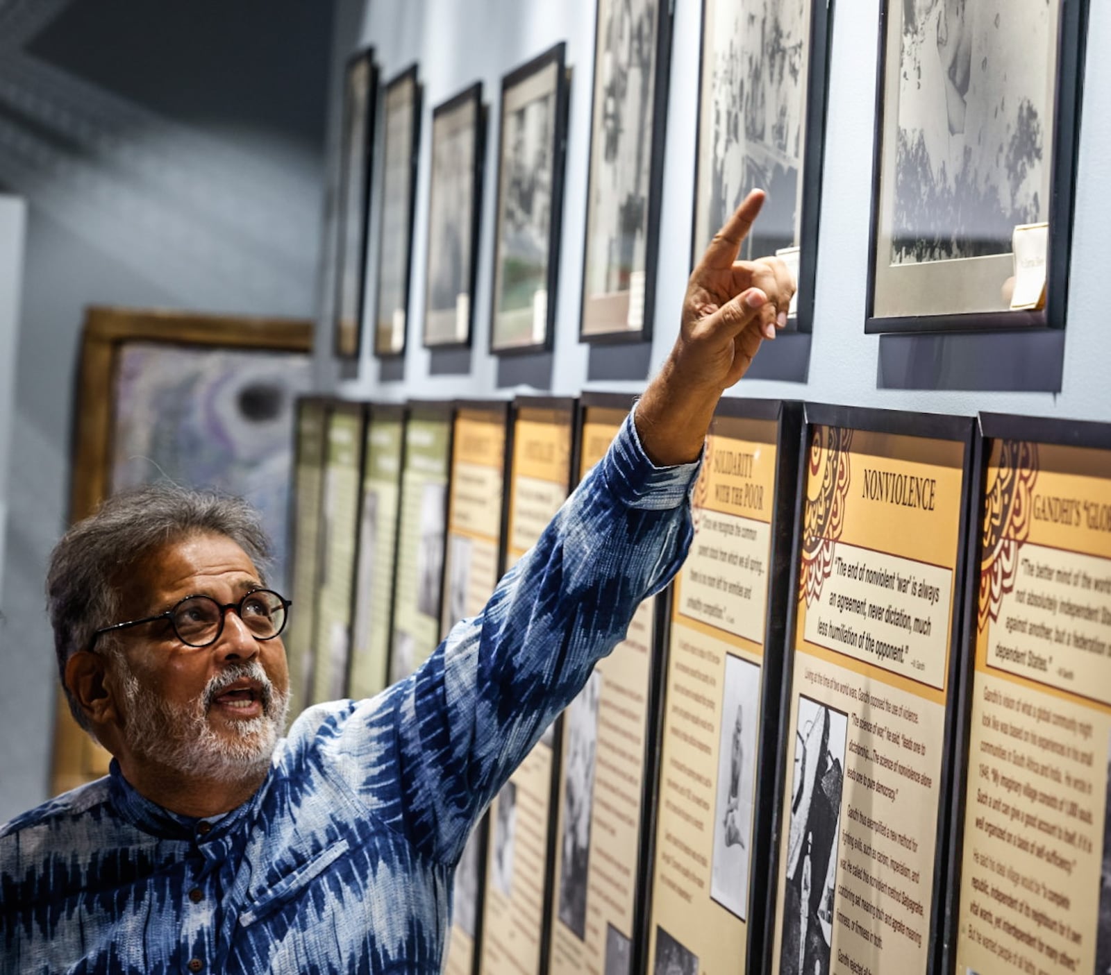 Tushar Arun Gandhi from Mumbai, India, the great-grandson of Mahatma Gandhi, was at the International Peace Museum in Dayton on Friday, Jan. 26, 2024. Gandhi points out photos of his great-grandfather that hang in the museum. JIM NOELKER/STAFF