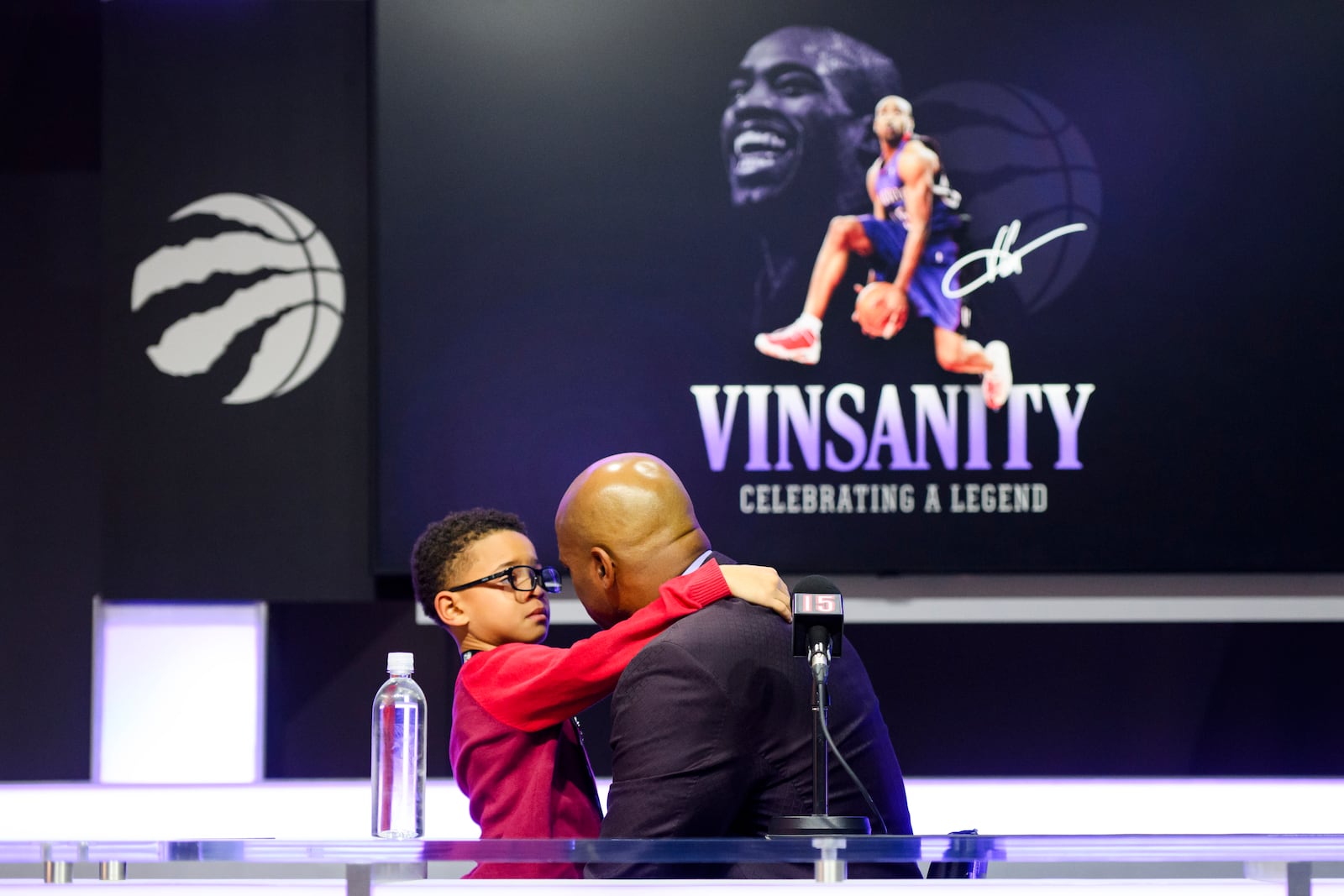 Former Toronto Raptors player Vince Carter is consoled by his son, Vince Carter Jr. while overcome by emotion when speaking to media ahead of his number retirement before an NBA basketball game between the Toronto Raptors and the Sacramento Kings at the Scotiabank arena in Toronto on Saturday, Nov. 2, 2024. (Christopher Katsarov/The Canadian Press via AP)