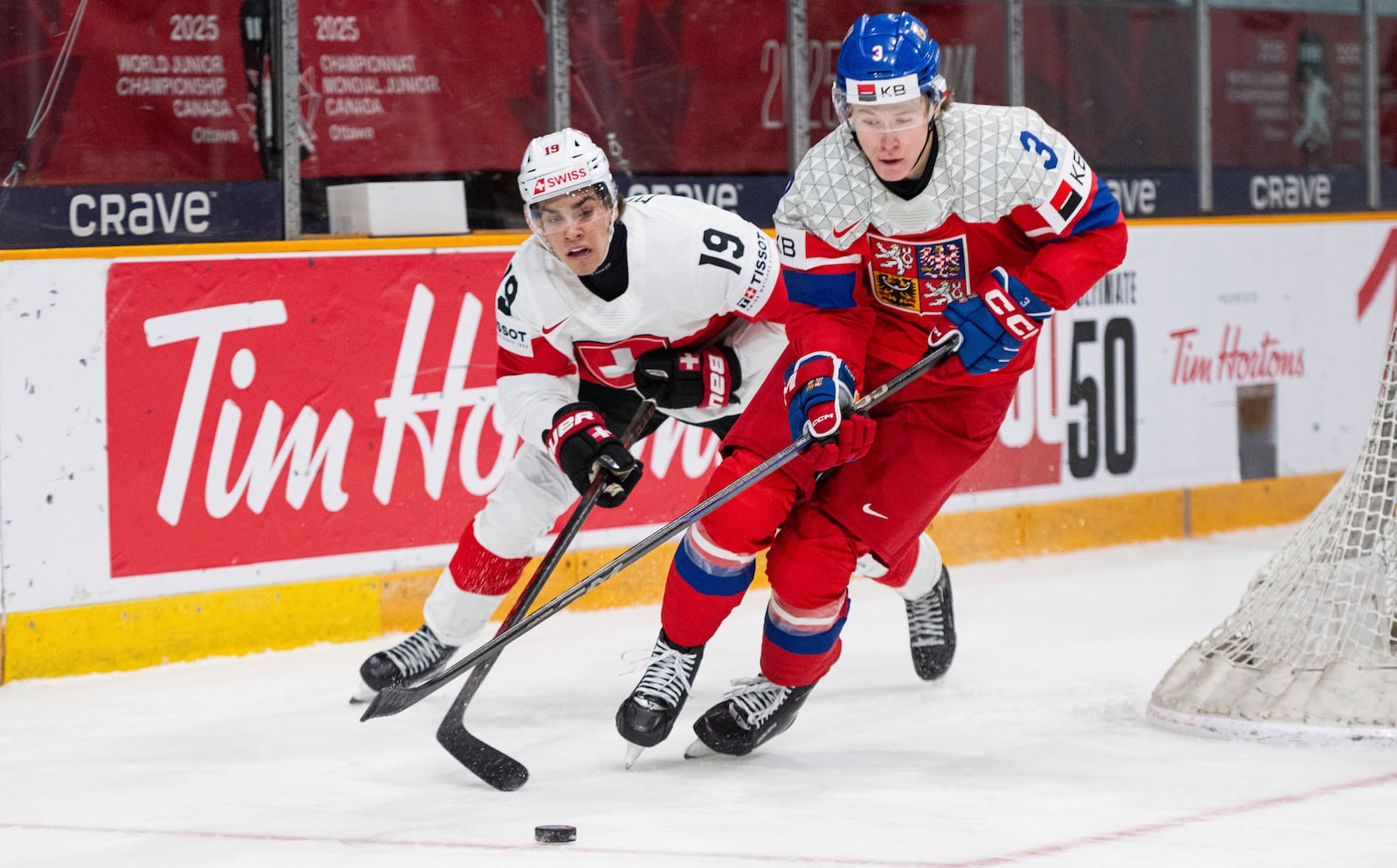 Switzerland forward Endo Meier (19) and Czechia defenseman Vojtech Port (3) battle for the puck during first-period IIHF World Junior Hockey Championship preliminary round game action in Ottawa, Ontario, Thursday, Dec. 26, 2024. (Spencer Colby/The Canadian Press via AP)