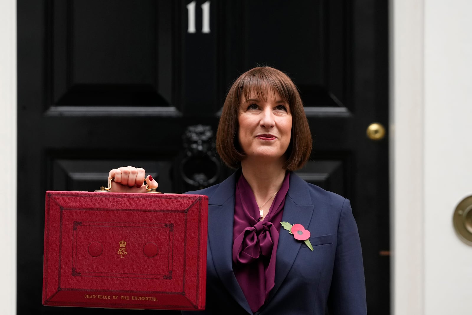 Britain's Chancellor of the Exchequer, Rachel Reeves, looks up as she holds up the traditional red ministerial box containing her budget speech, as she poses for the media outside No 11 Downing Street, before departing to the House of Commons to deliver the budget in London, Wednesday, Oct. 30, 2024. (AP Photo/Kirsty Wigglesworth)