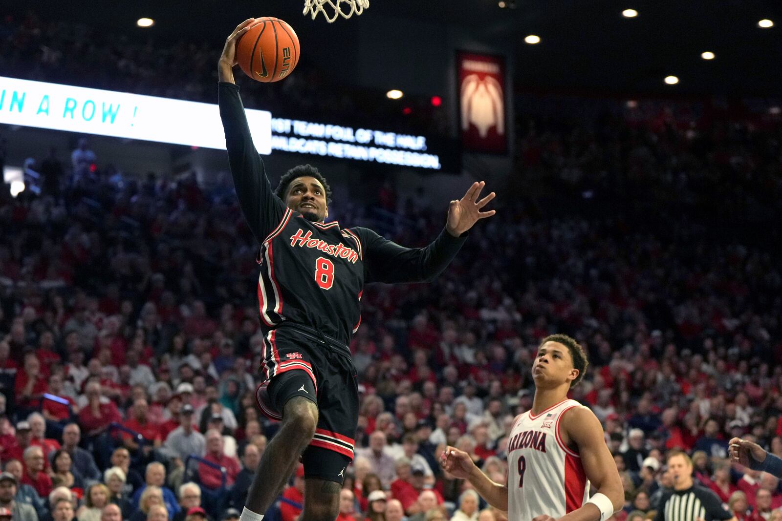 Houston guard Mylik Wilson (8) drives past Arizona forward Carter Bryant during the first half of an NCAA college basketball game, Saturday, Feb. 15, 2025, in Tucson, Ariz. (AP Photo/Rick Scuteri)