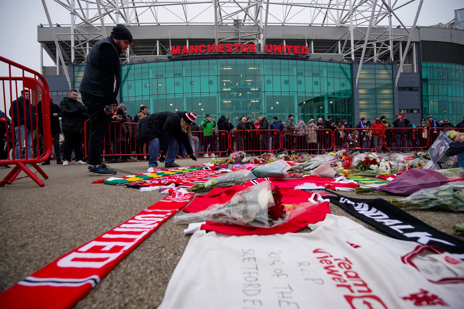 People lay flowers in memory of Denis Law prior the English Premier League soccer match between Manchester United and Brighton and Hove Albion, at the Old Trafford stadium in Manchester, England, Sunday, Jan. 19, 2025. (AP Photo/Dave Thompson)