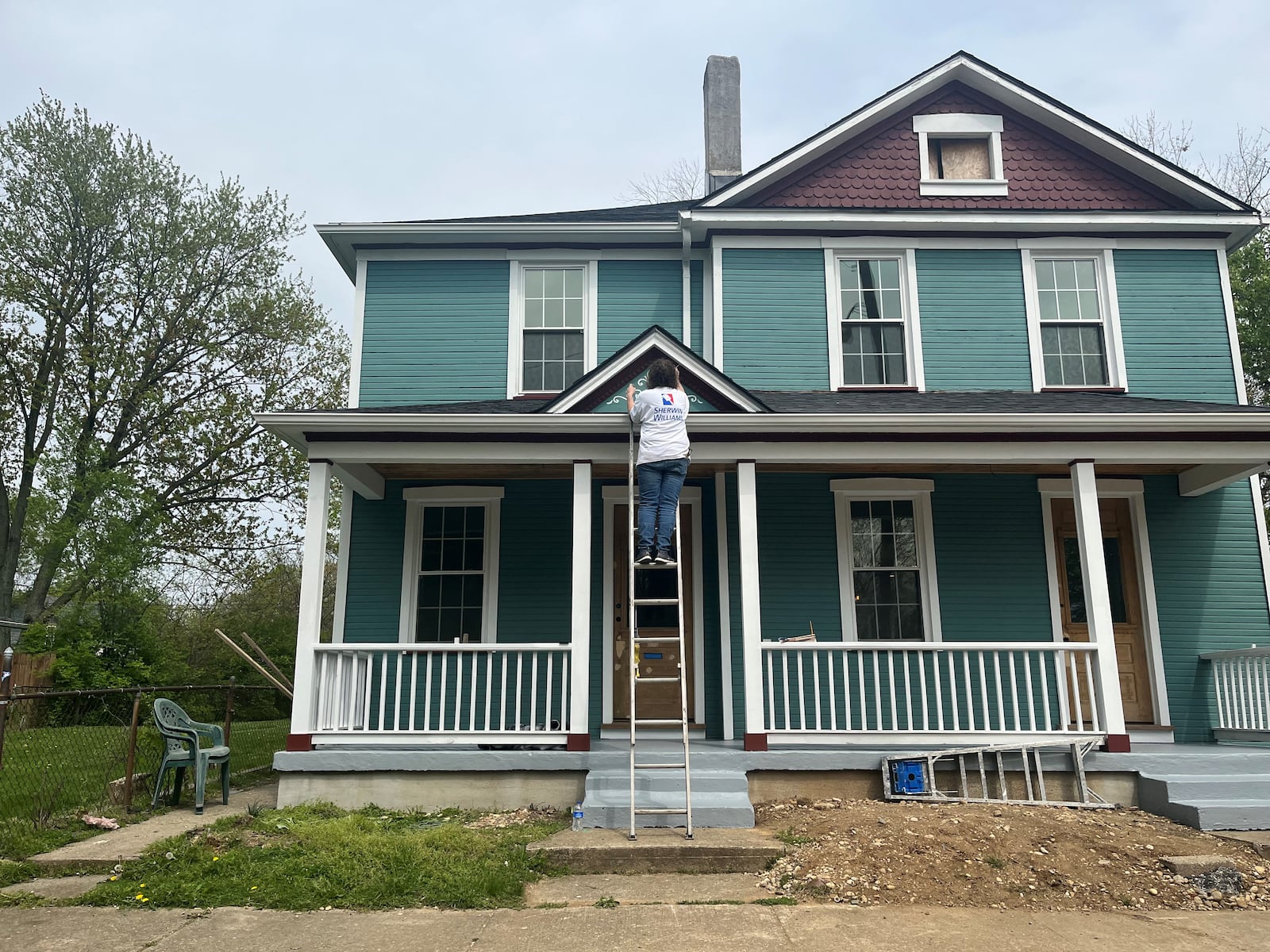 A woman works on the exterior of a home in the St. Anne's Hill neighborhood. CORNELIUS FROLIK / STAFF