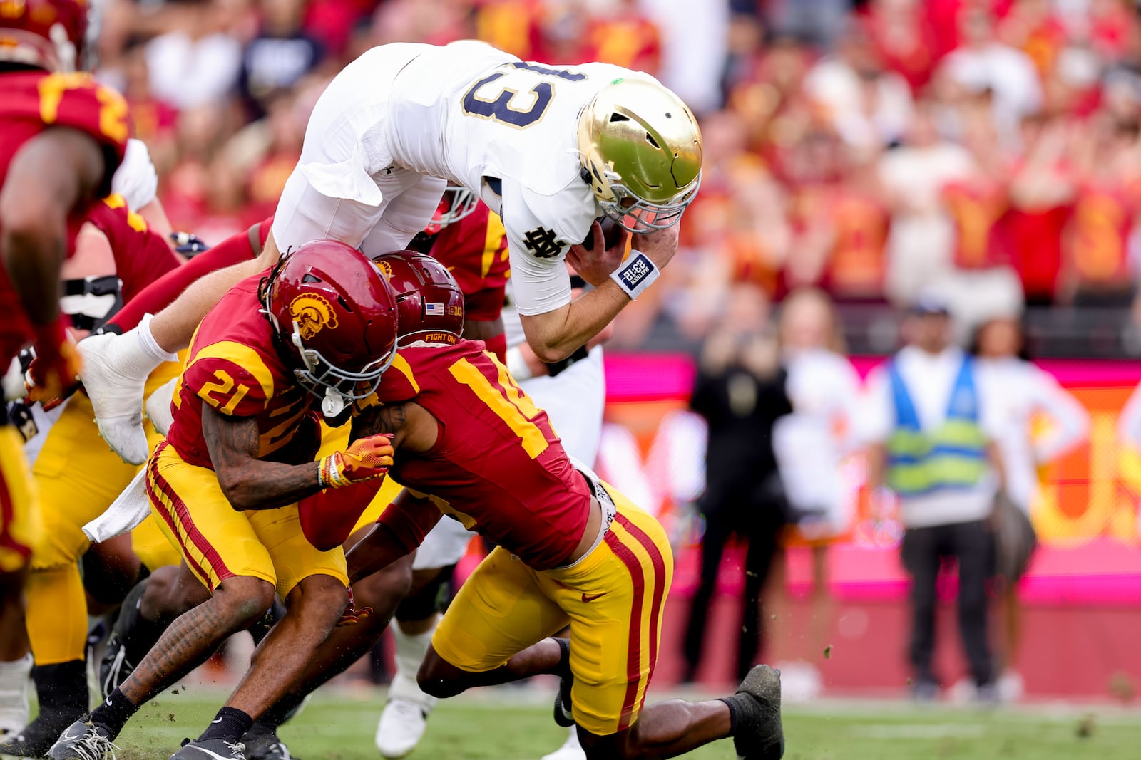 Notre Dame quarterback Riley Leonard, top, dives over Southern California cornerback Greedy Vance Jr., left, and cornerback Jacobe Covington during the first half of an NCAA football game, Saturday, Nov. 30, 2024, in Los Angeles. (AP Photo/Ryan Sun)