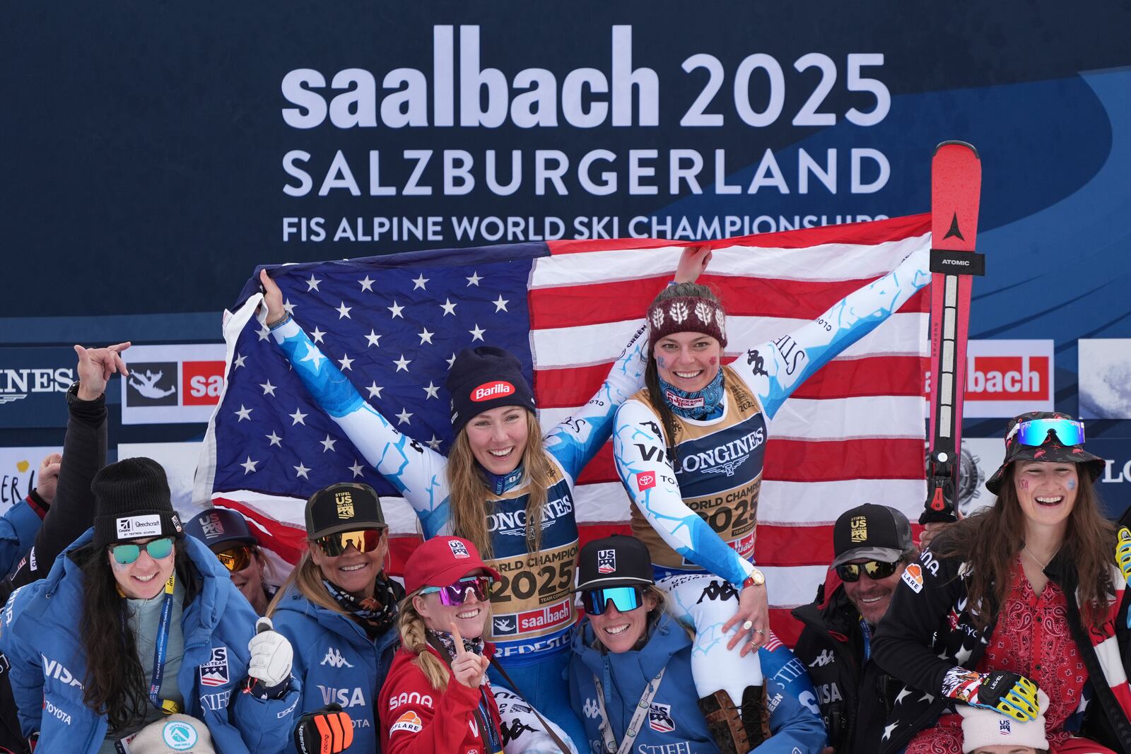 United States' Mikaela Shiffrin, left, and United States' Breezy Johnson, celebrate on the podium with the team after winning the gold medal in a women's team combined event, at the Alpine Ski World Championships, in Saalbach-Hinterglemm, Austria, Tuesday, Feb. 11, 2025. (AP Photo/Giovanni Auletta)