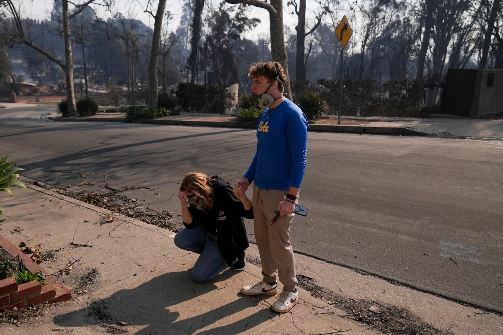 Kathleen Orlinksy prays while holding hands with her son David after finding out their home was spared in the aftermath of the Palisades Fire in the Pacific Palisades neighborhood of Los Angeles, Thursday, Jan. 9, 2025. (AP Photo/Jae C. Hong)