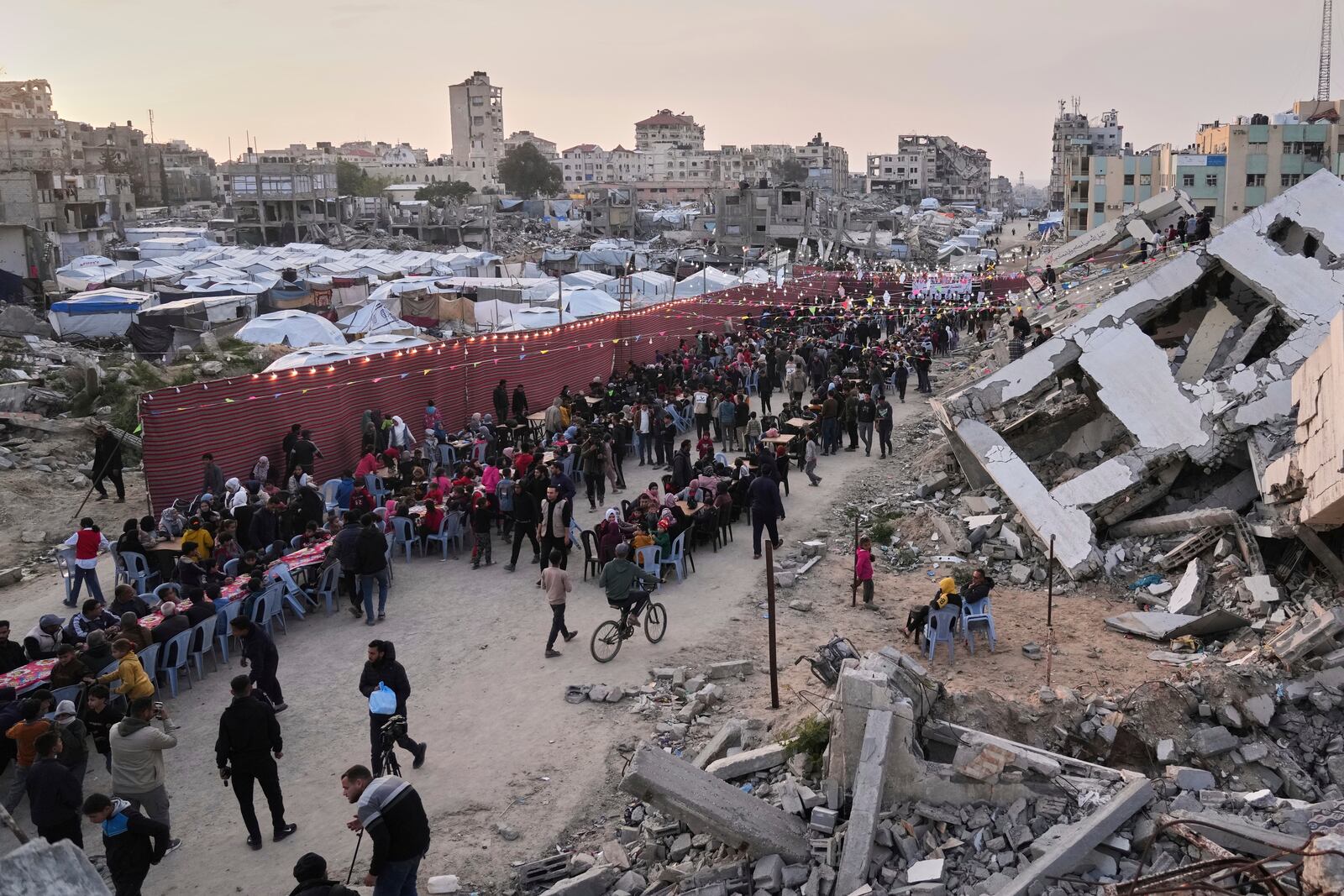 Palestinians sit at a large table surrounded by the rubble of destroyed homes and buildings as they gather for iftar, the fast-breaking meal, during Ramadan in Gaza City, Thursday March 6, 2025 (AP Photo/Abdel Kareem Hana)