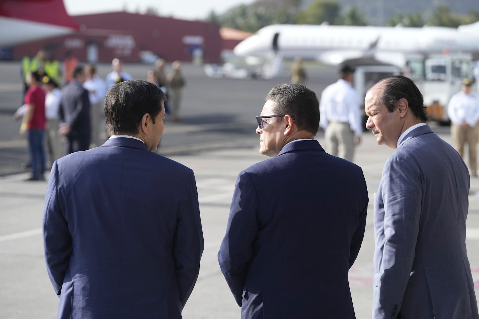 Secretary of State Marco Rubio, left, Frank Alexis Abrego, Panama's Minister of Public Security, center, and Panama's Foreign Minister Javier Martinez-Acha, watch as people board a repatriation flight bound for Colombia at Albrook Airport in Panama City, Monday, Feb. 3, 2025. (AP Photo/Mark Schiefelbein, Pool)